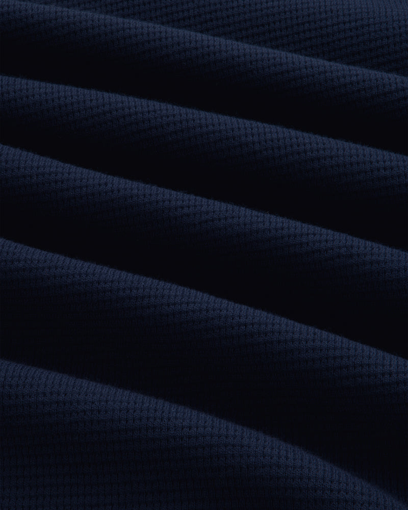 Close-up of a dark blue Long-Sleeve Waffle Henley with a waffle-knit texture and soft folds.