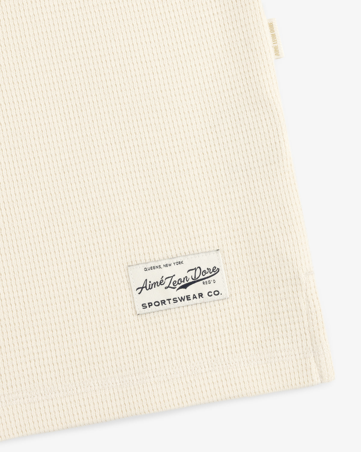 Off-white waffle-knit Long-Sleeve Waffle Henley with a rectangular brand label stitched near the hem.
