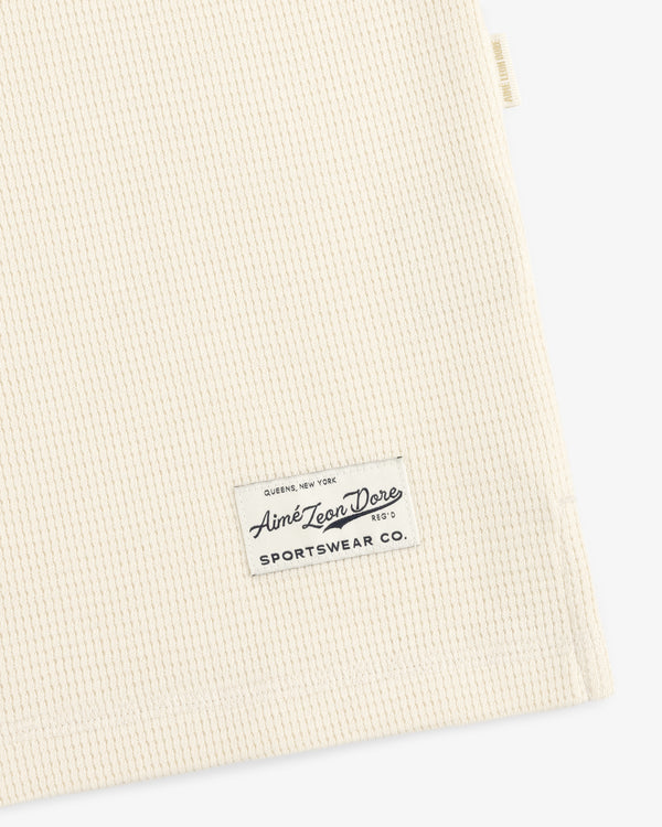Off-white waffle-knit Long-Sleeve Waffle Henley with a rectangular brand label stitched near the hem.