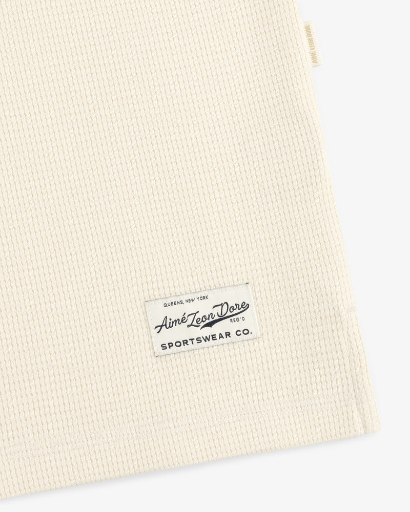 Off-white waffle-knit Long-Sleeve Waffle Henley with a rectangular brand label stitched near the hem.
