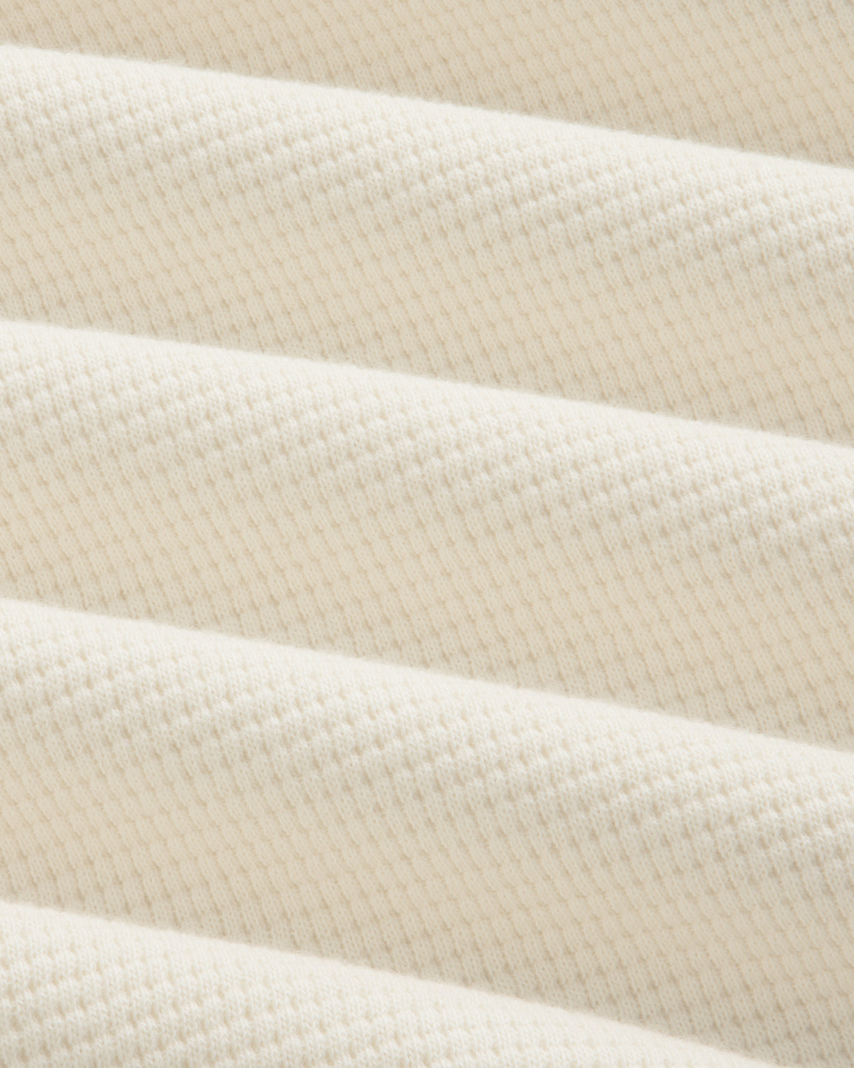 Off-white Long-Sleeve Waffle Henley fabric with a textured waffle-knit pattern in draped folds.