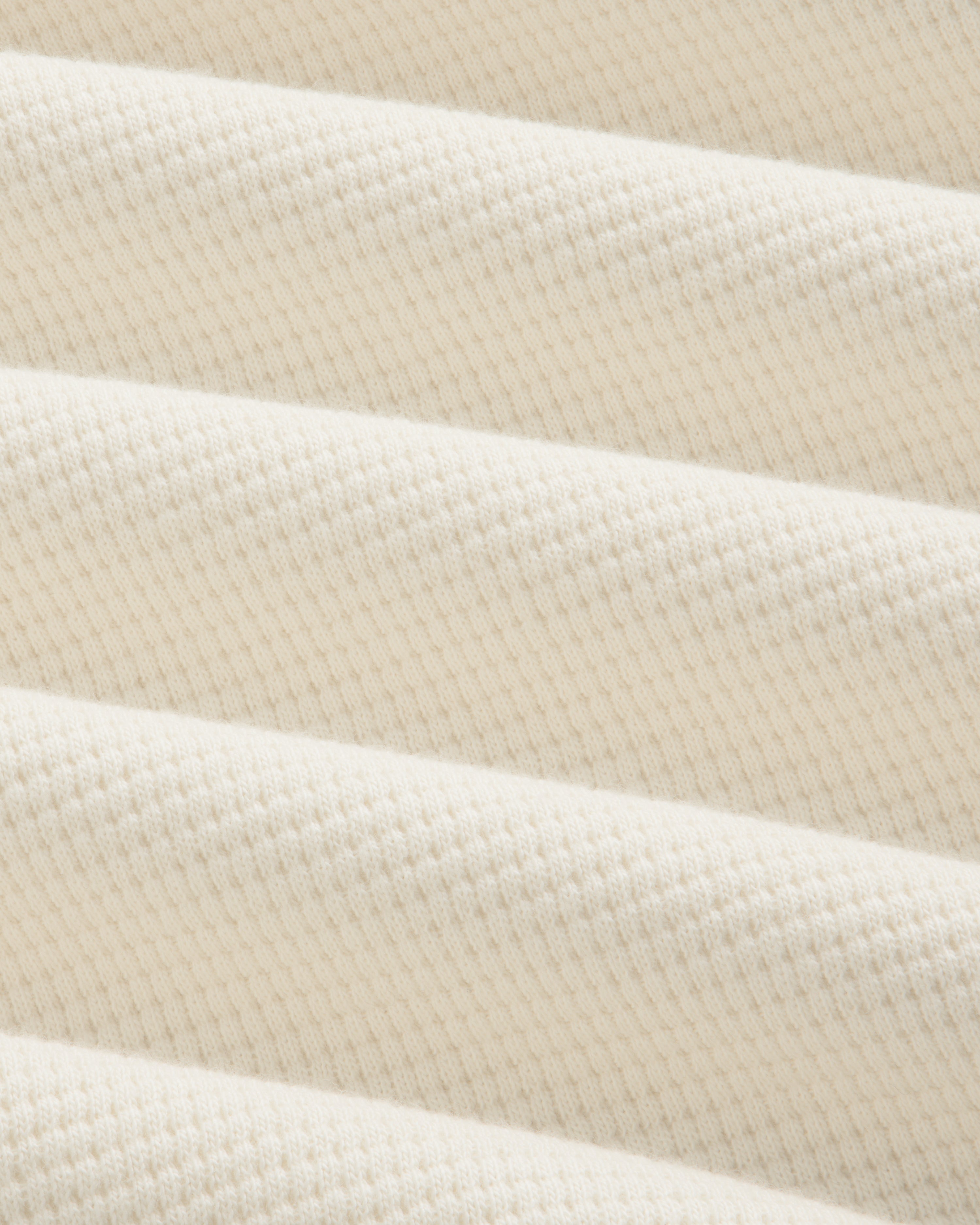 Off-white Long-Sleeve Waffle Henley fabric with a textured waffle-knit pattern in draped folds.