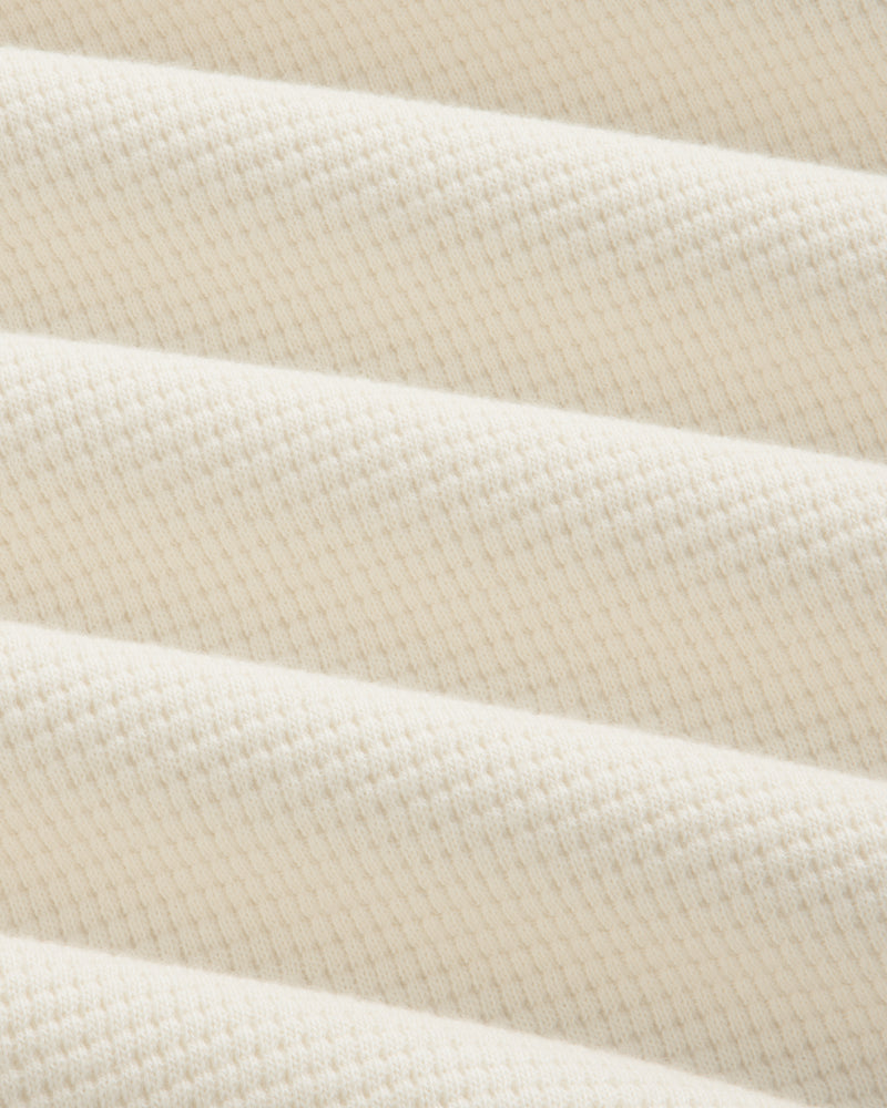 Off-white Long-Sleeve Waffle Henley fabric with a textured waffle-knit pattern in draped folds.
