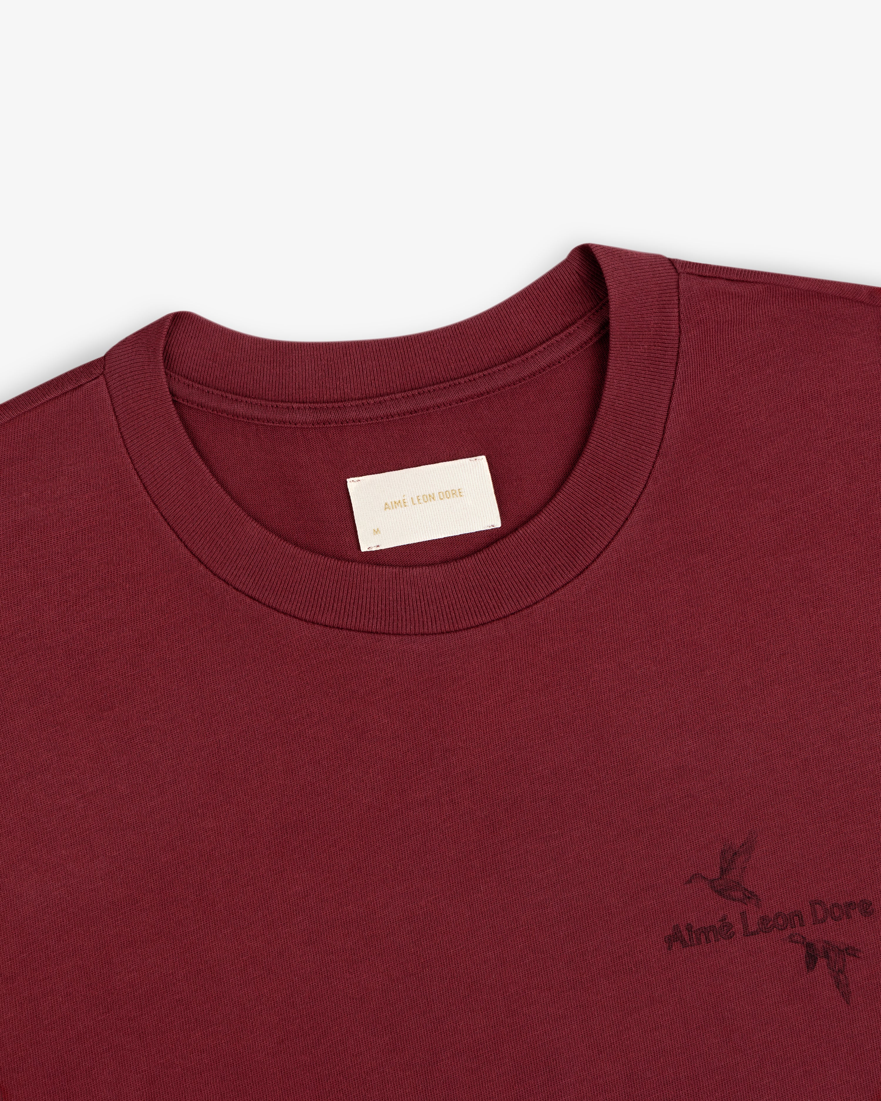 Maroon Long-Sleeve Retriever Tee with a logo and small bird graphic on the chest.