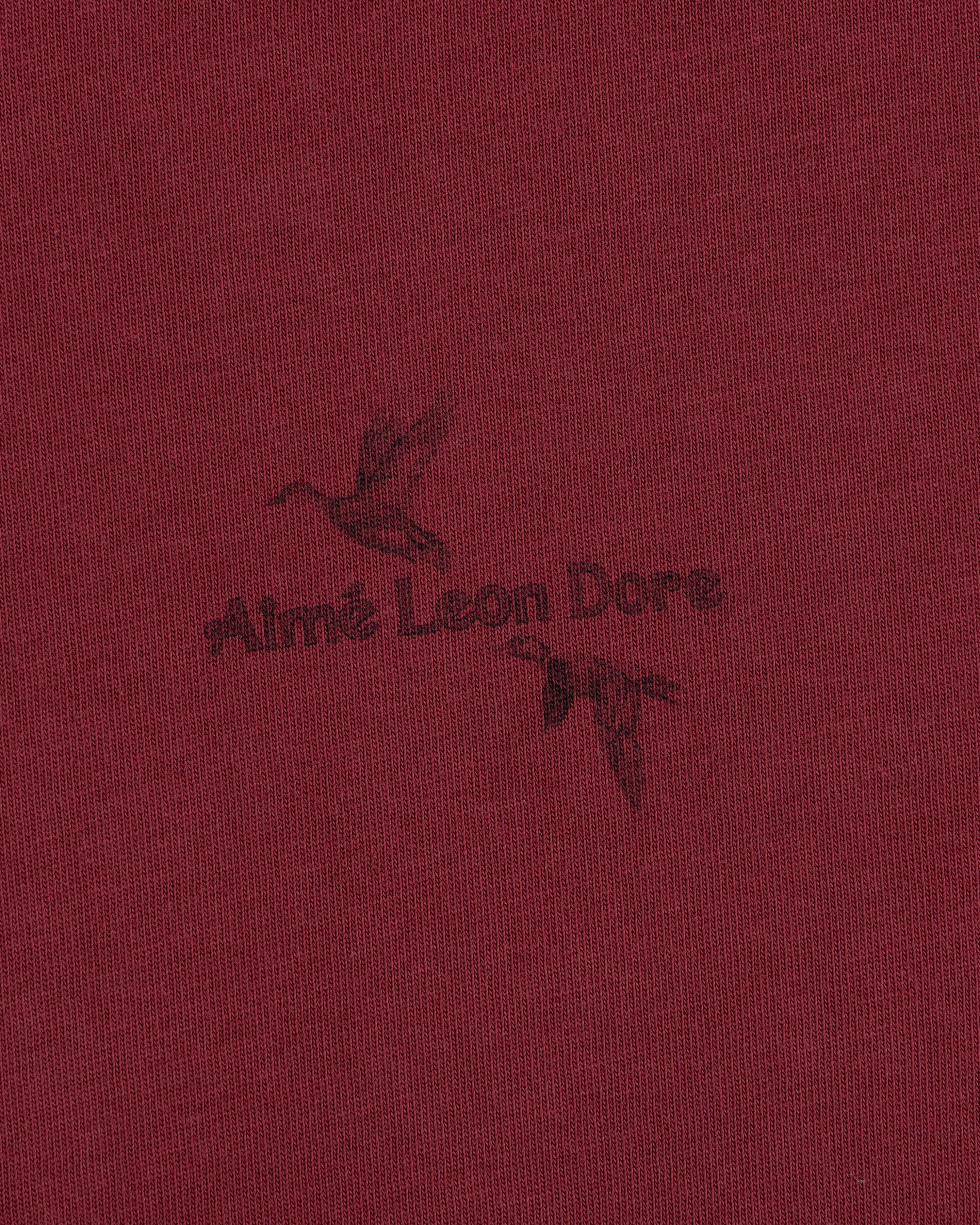 Long-Sleeve Retriever Tee in maroon, featuring a dark print of two flying ducks and the text Aimé Leon Dore.