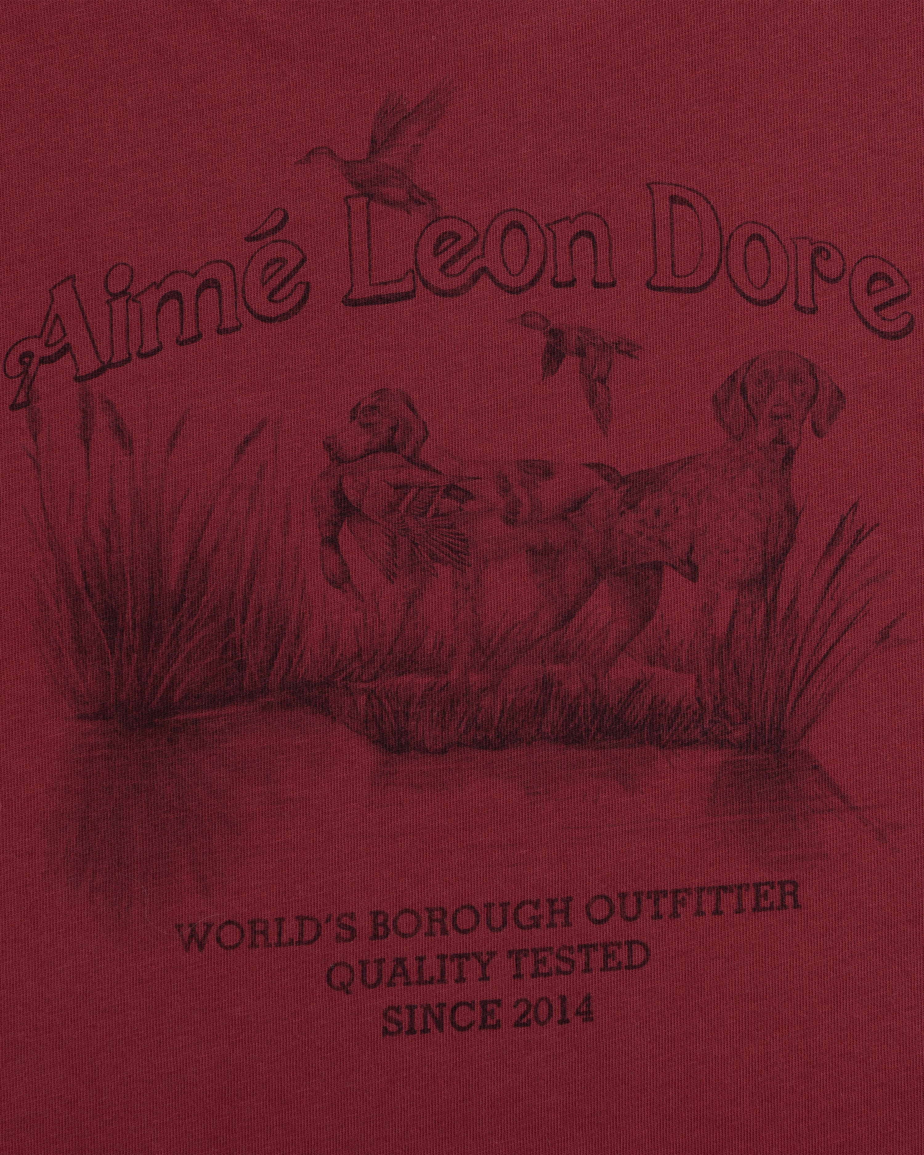 Long-Sleeve Retriever Tee in red with a hunting scene of two dogs and birds above WORLDS BOROUGH OUTFITTER text.