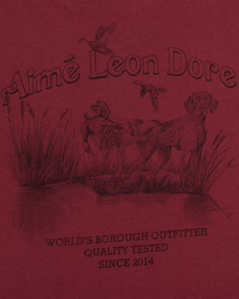 Long-Sleeve Retriever Tee in red with a hunting scene of two dogs and birds above WORLDS BOROUGH OUTFITTER text.