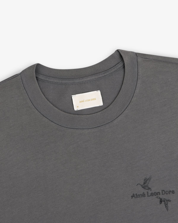 Dark grey Long-Sleeve Retriever Tee with a small embroidered bird design and brand text.