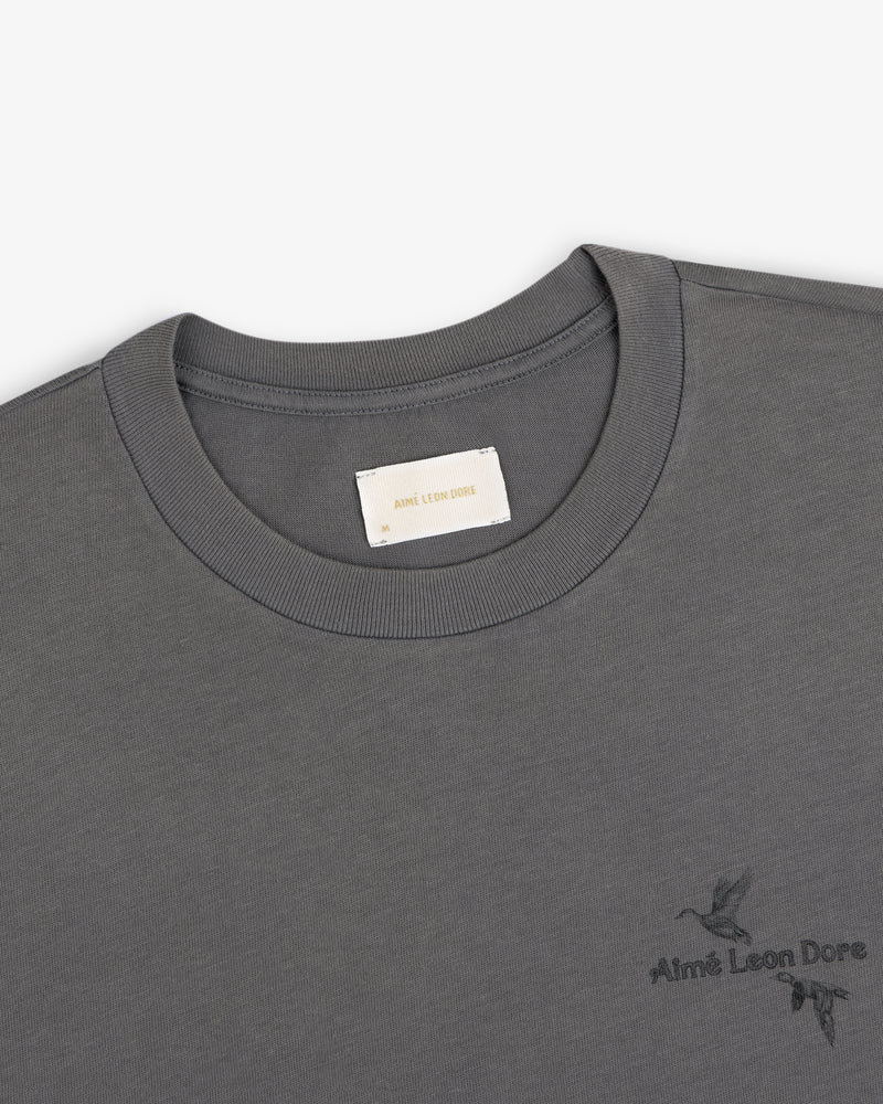 Dark grey Long-Sleeve Retriever Tee with a small embroidered bird design and brand text.