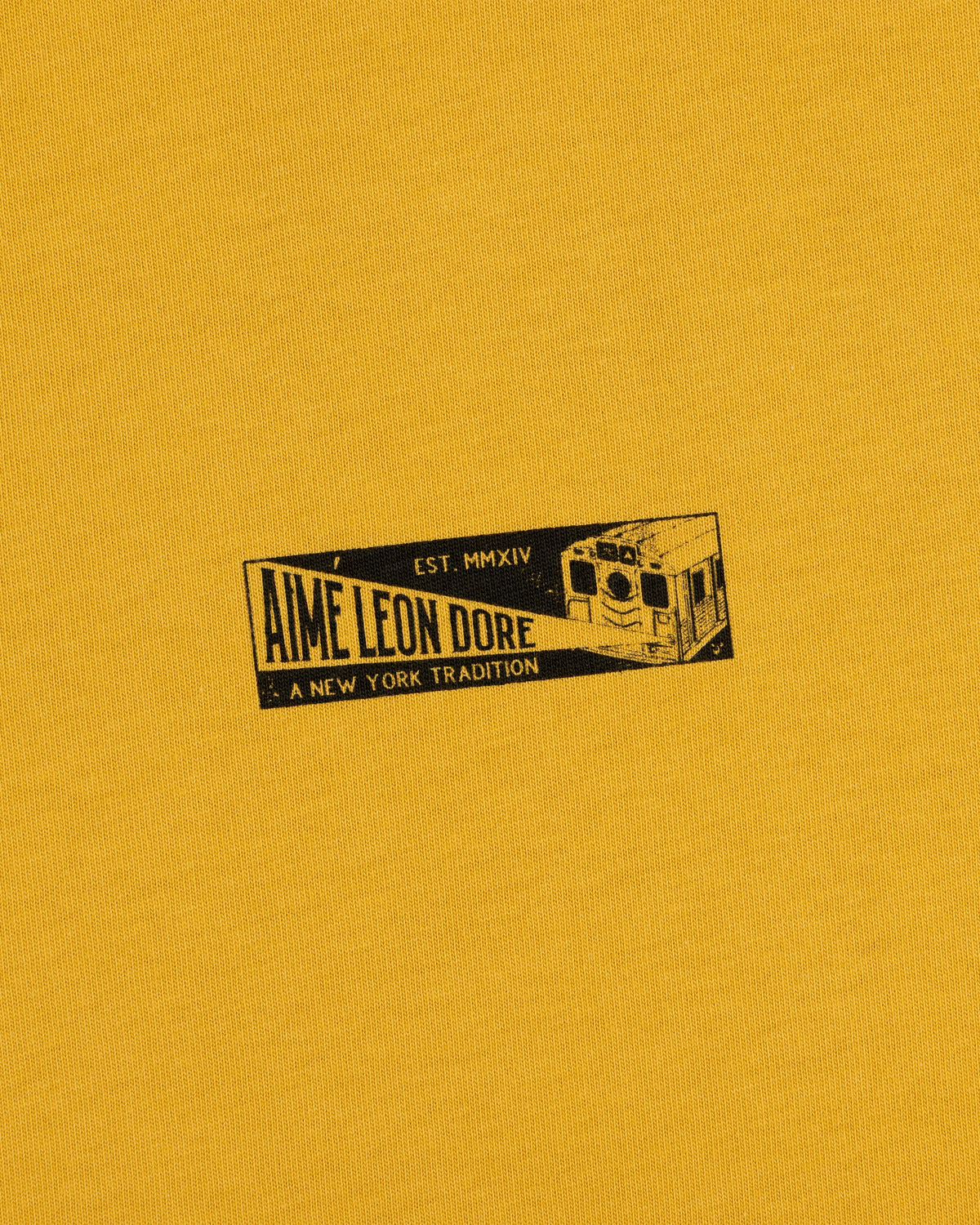 Mustard yellow Aimé Transit Tee featuring a graphic of a New York subway car with the text Aime Leon Dore, Est. MMXIV.