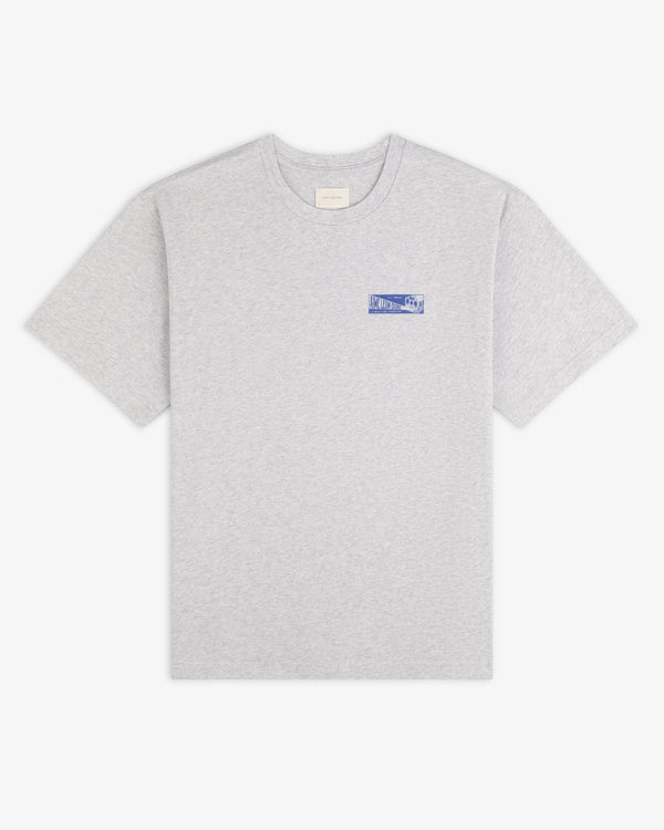 Grey Aimé Transit Tee with a small blue graphic on the left chest.