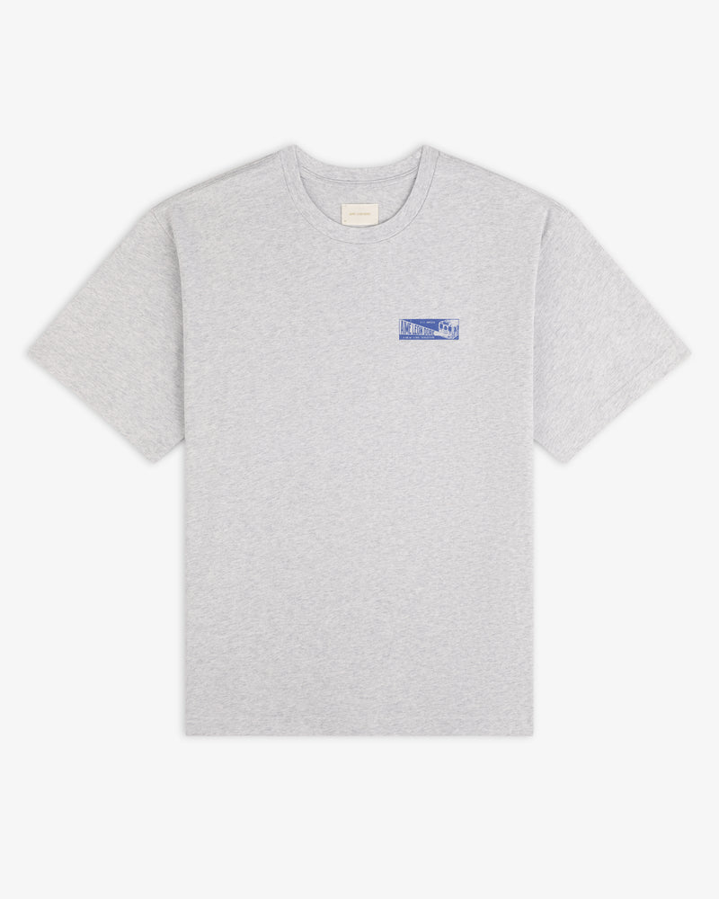 Grey Aimé Transit Tee with a small blue graphic on the left chest.