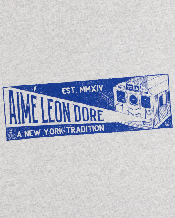 Light gray Aimé Transit Tee with a blue subway car graphic and text reading Aime Leon Dore, Est. MMXIV, A New York Tradition.