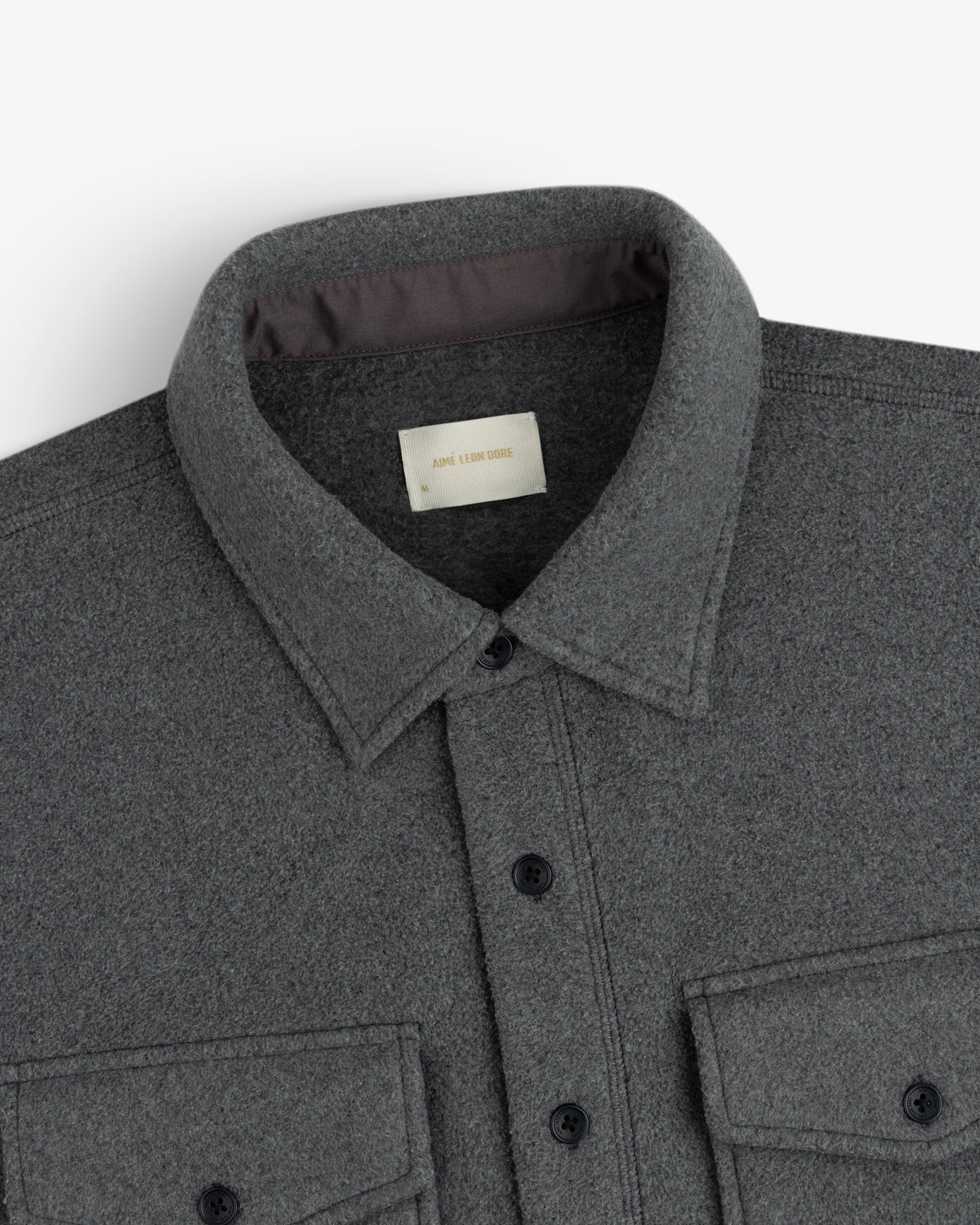 Close-up of Melange Fleece Shirt in gray with collar and two chest pockets, shown on a white background.