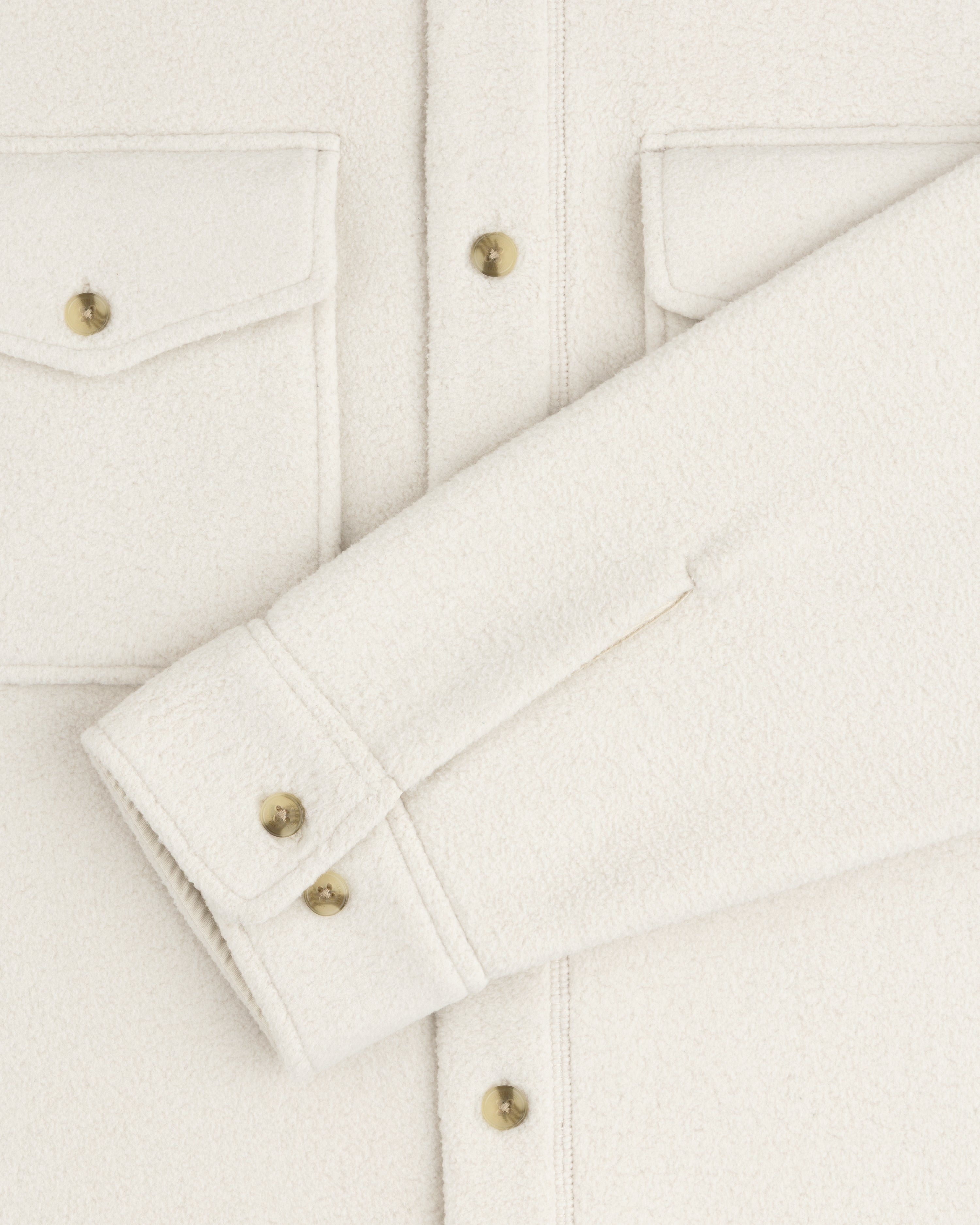 Melange Fleece Shirt in off-white with flap pockets, gold buttons, one sleeve laid flat across the front.