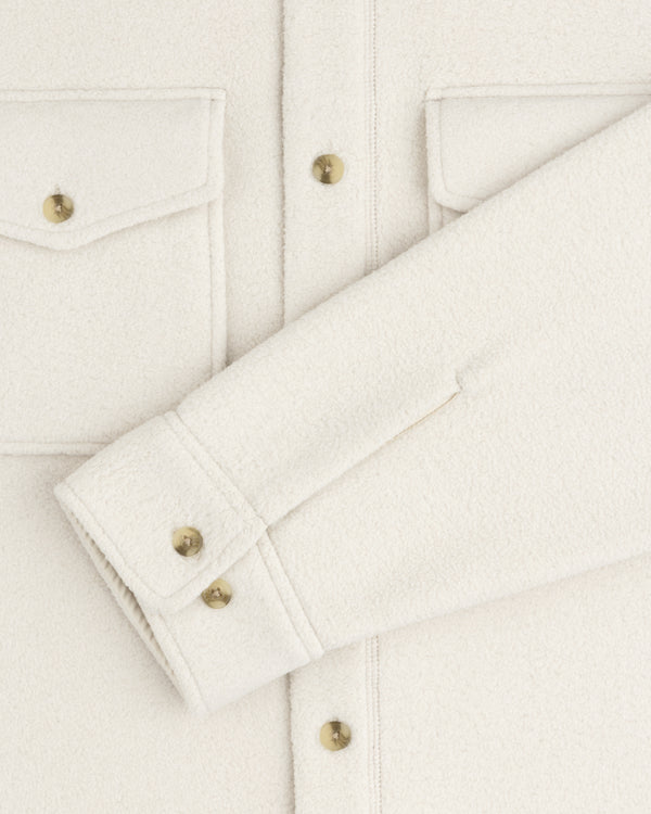Melange Fleece Shirt in off-white with flap pockets, gold buttons, one sleeve laid flat across the front.