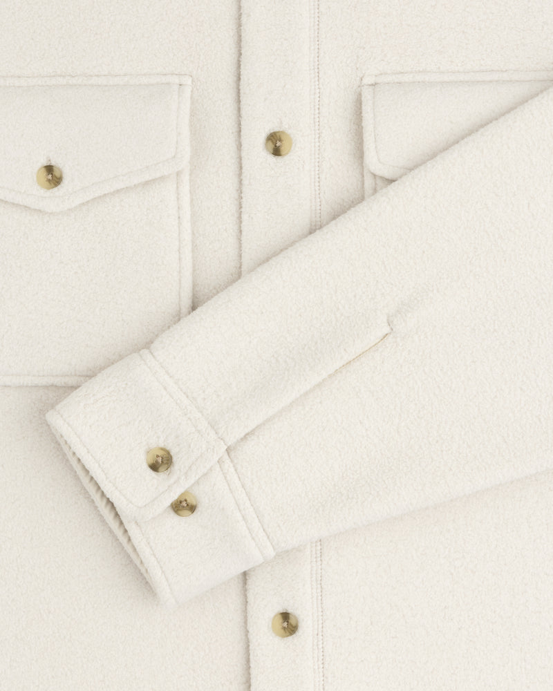 Melange Fleece Shirt in off-white with flap pockets, gold buttons, one sleeve laid flat across the front.