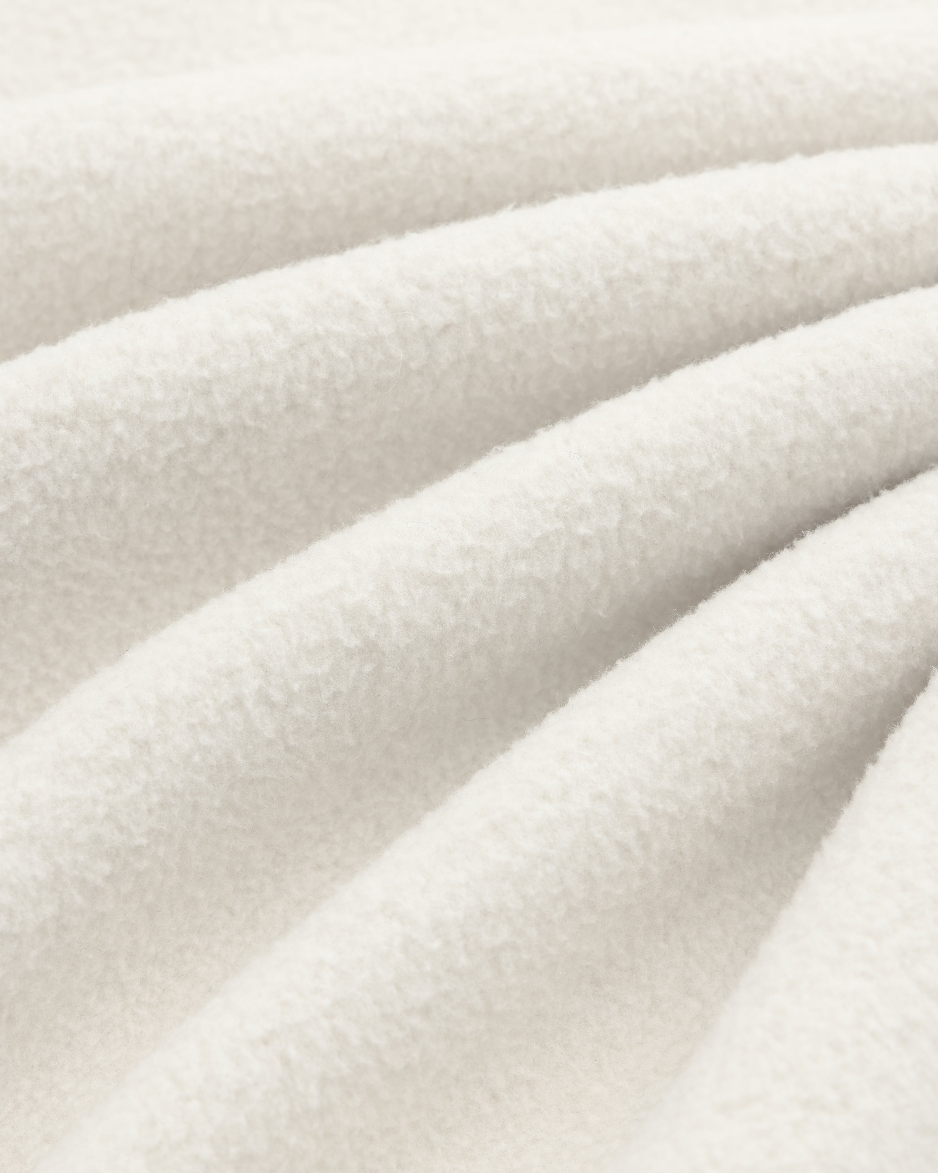 Close-up of Melange Fleece Shirt’s soft, off-white fabric with gentle folds and a textured, fuzzy surface.