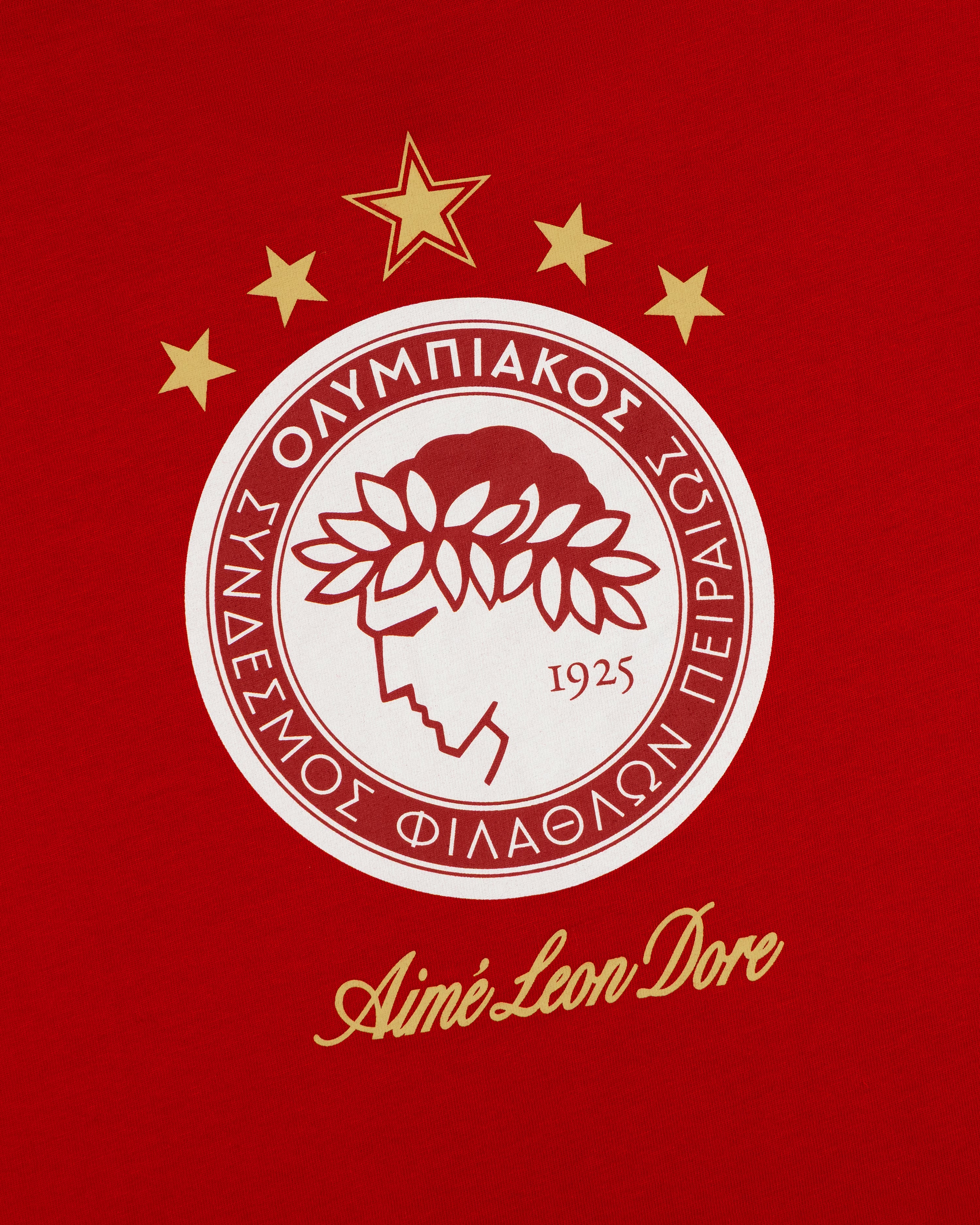 Red ALD / Olympiacos F.C. Souvenir Tee featuring a circular logo, five gold stars, and Aimé Leon Dore text.