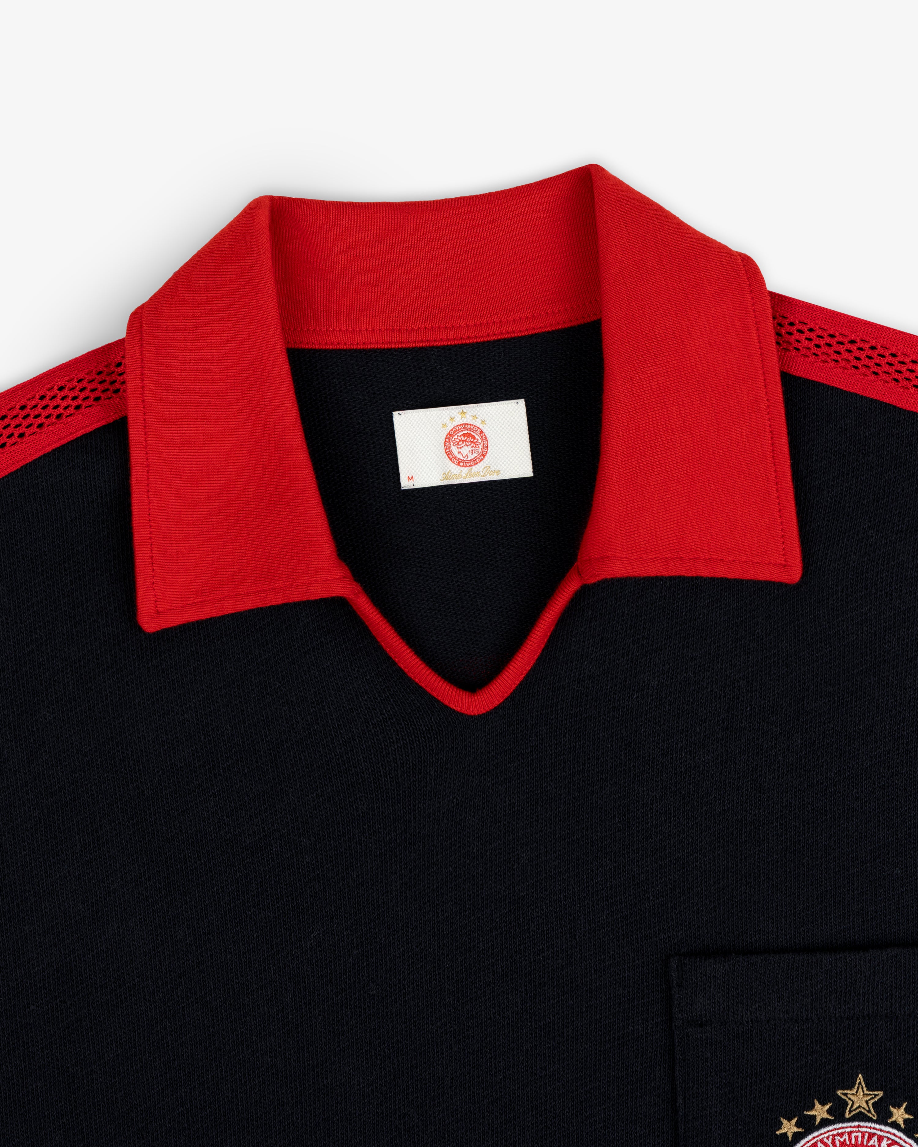 ALD / Olympiacos F.C. Heritage Ringer Polo: black shirt with red collar, mesh shoulders, and gold star chest embroidery.