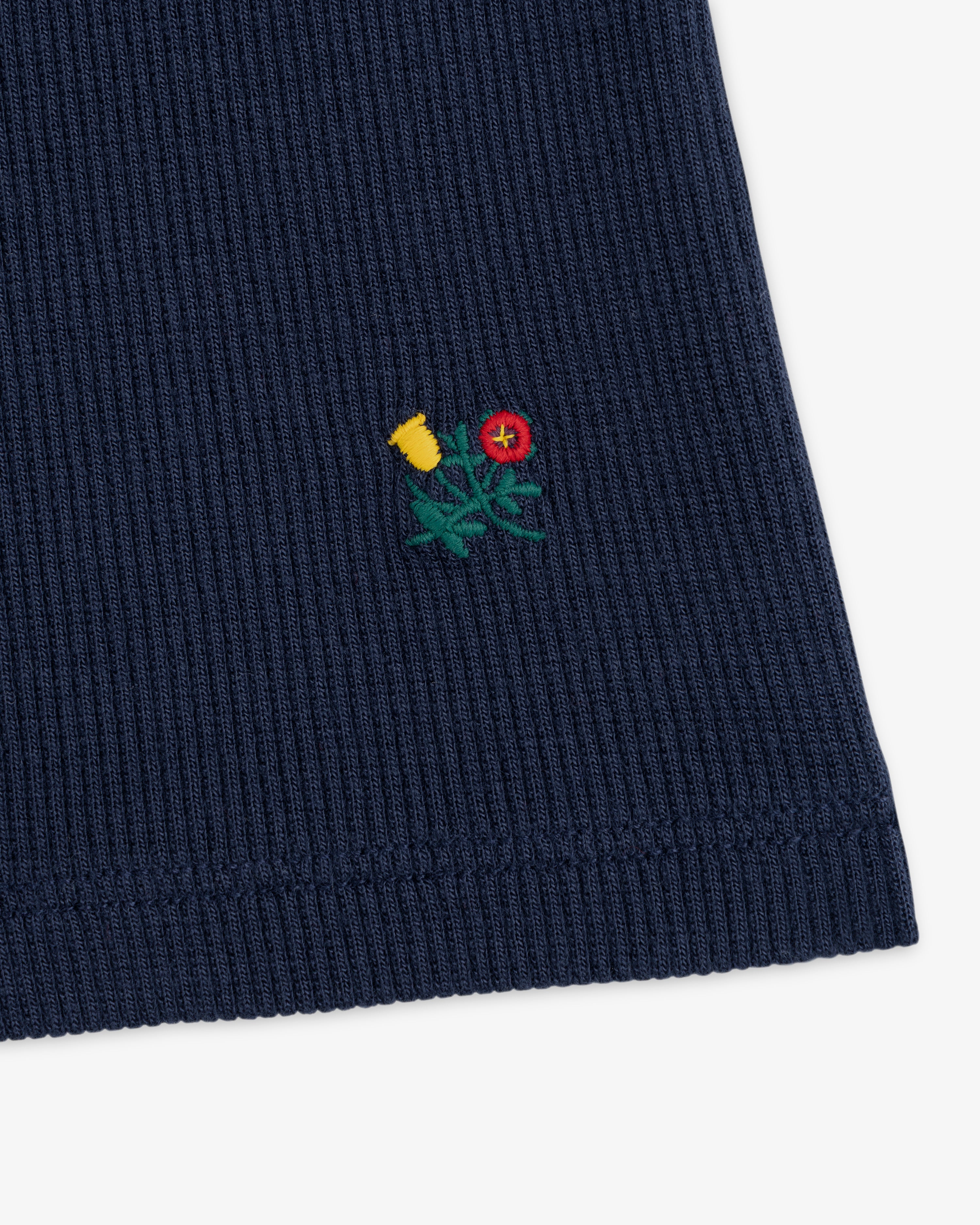 Navy Ribbed Mockneck Long-Sleeve Tee with a small embroidered yellow and red flower design.