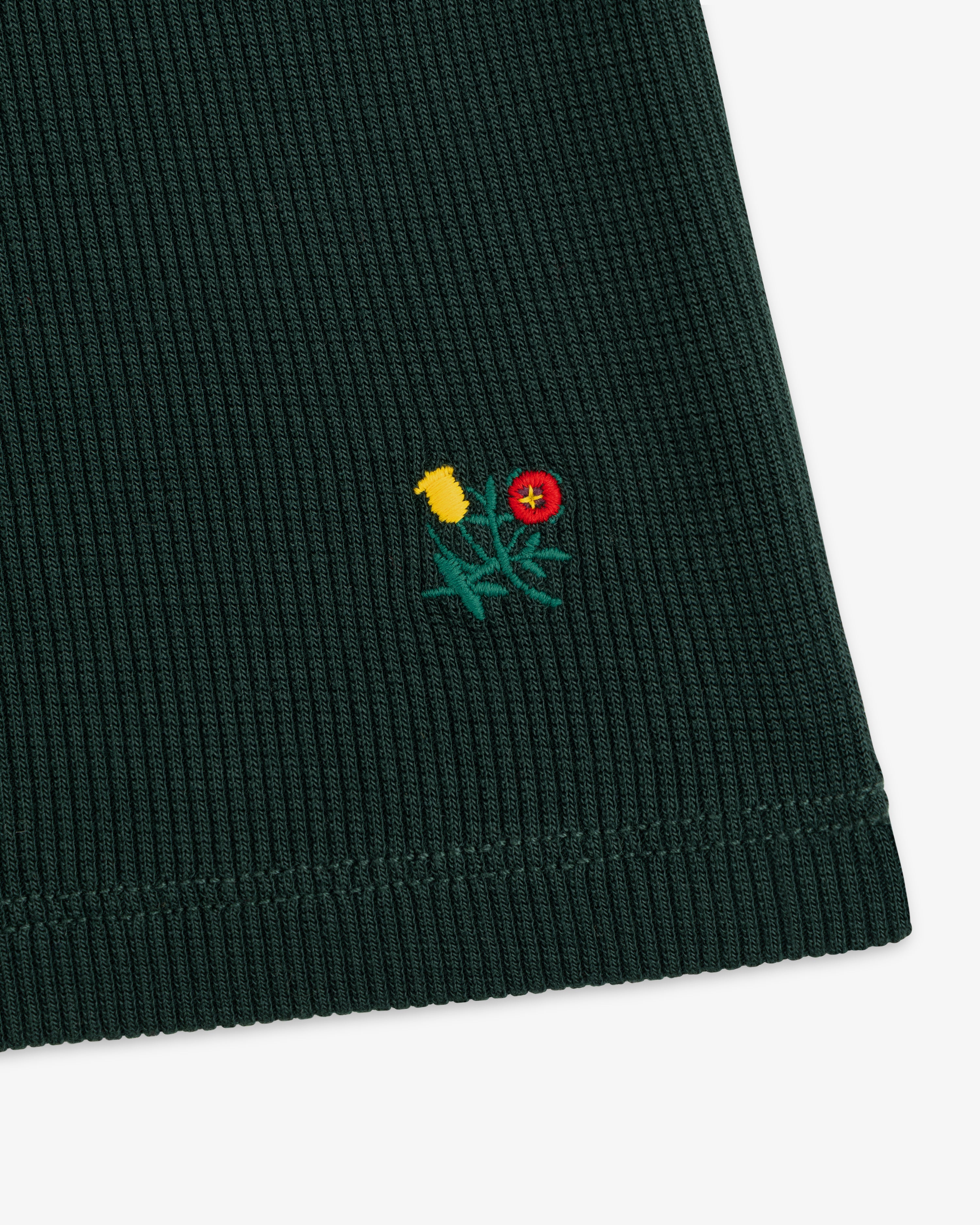 Dark green ribbed Ribbed Mockneck Long-Sleeve Tee with a small embroidered yellow and red floral design.