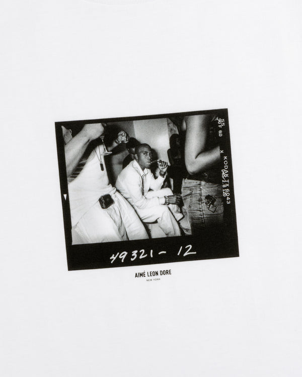 Black and white film contact sheet print of The Esco Tee featuring a man at a table with people around him.