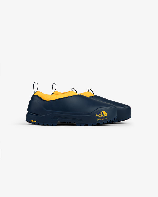 ALD / The North Face Base Camp Mule: navy slip-ons with yellow lining, logo on side, on white background.