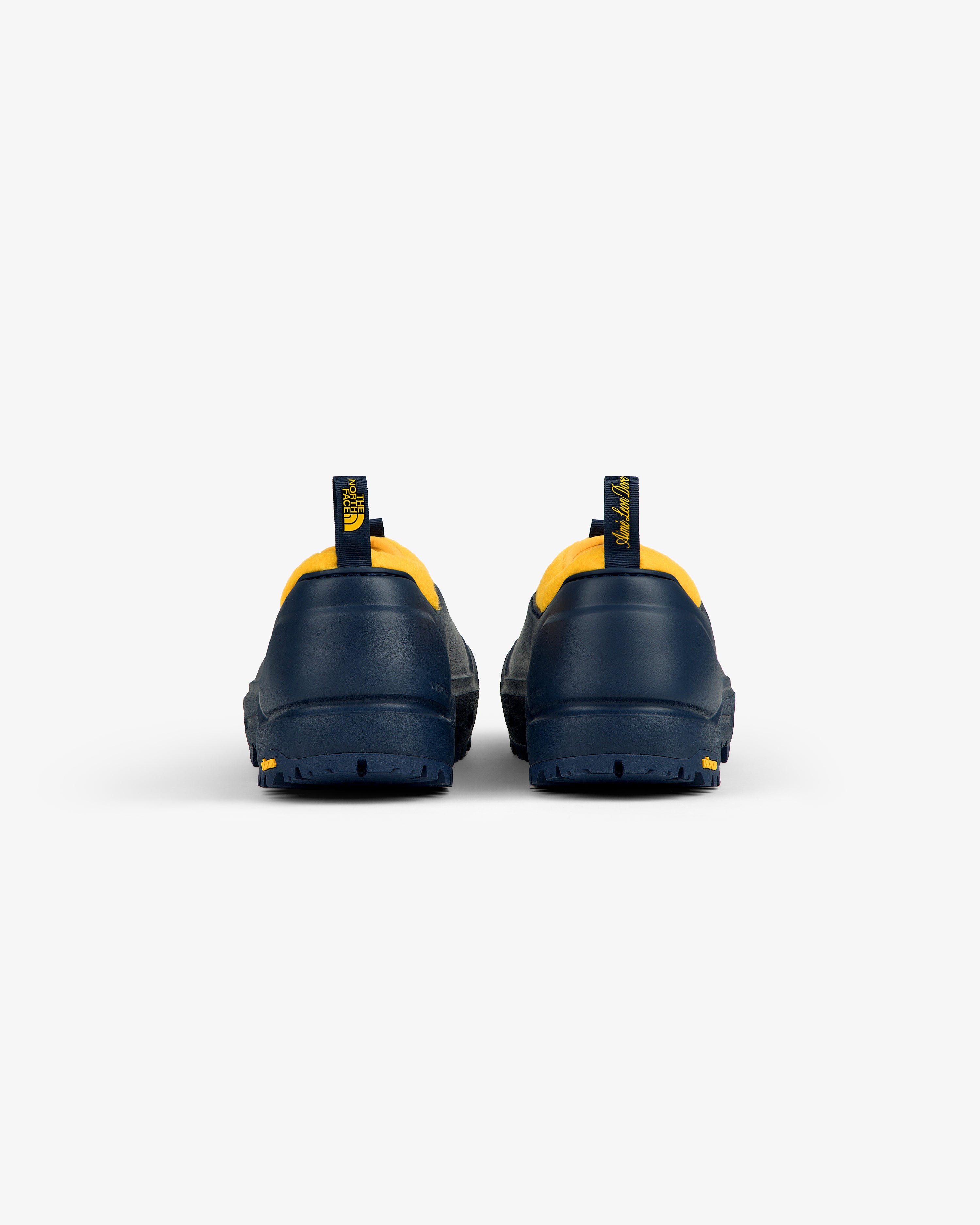 ALD / The North Face Base Camp Mule in navy with yellow trim, rear view, on a plain white background.