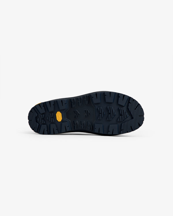 Dark blue sole of ALD / The North Face Base Camp Mule with deep treads and a small yellow label, viewed from below.