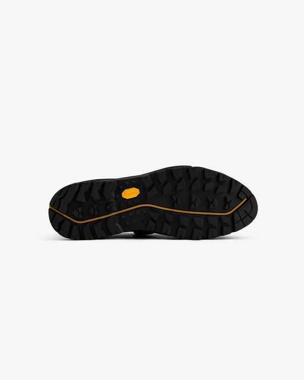 Black Vibram sole of ALD/The North Face Verto Alpine GORE-TEX Hiking Shoes, rugged tread, yellow logo, bottom view.