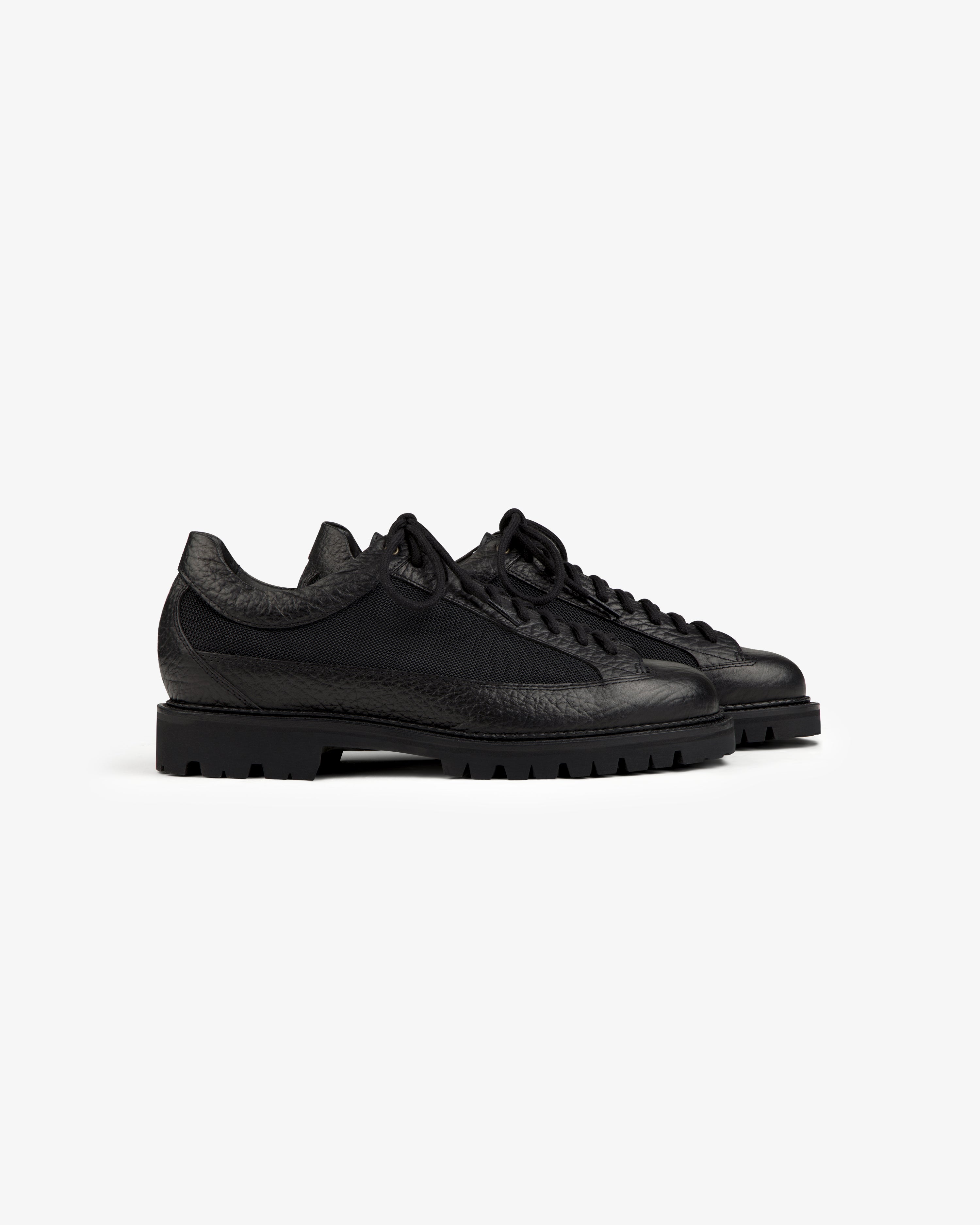 Field Boot: black low-top lace-up shoes with textured leather panels and thick lugged soles.