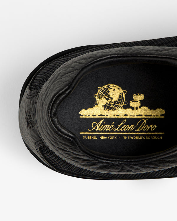 Black leather Field Boot insole with a gold globe emblem reading Aimé Leon Dore, Queens, New York.