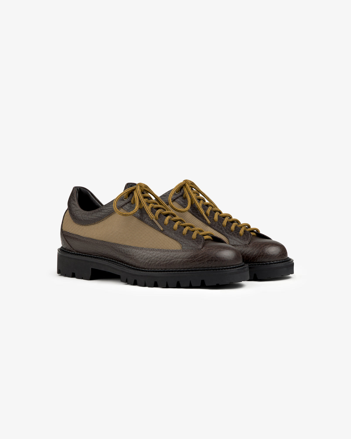 Field Boot low-top lace-up shoes in dark textured leather with tan side panels and thick black lugged soles.