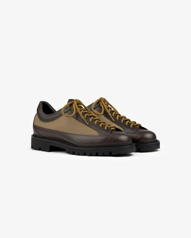 Field Boot low-top lace-up shoes in dark textured leather with tan side panels and thick black lugged soles.