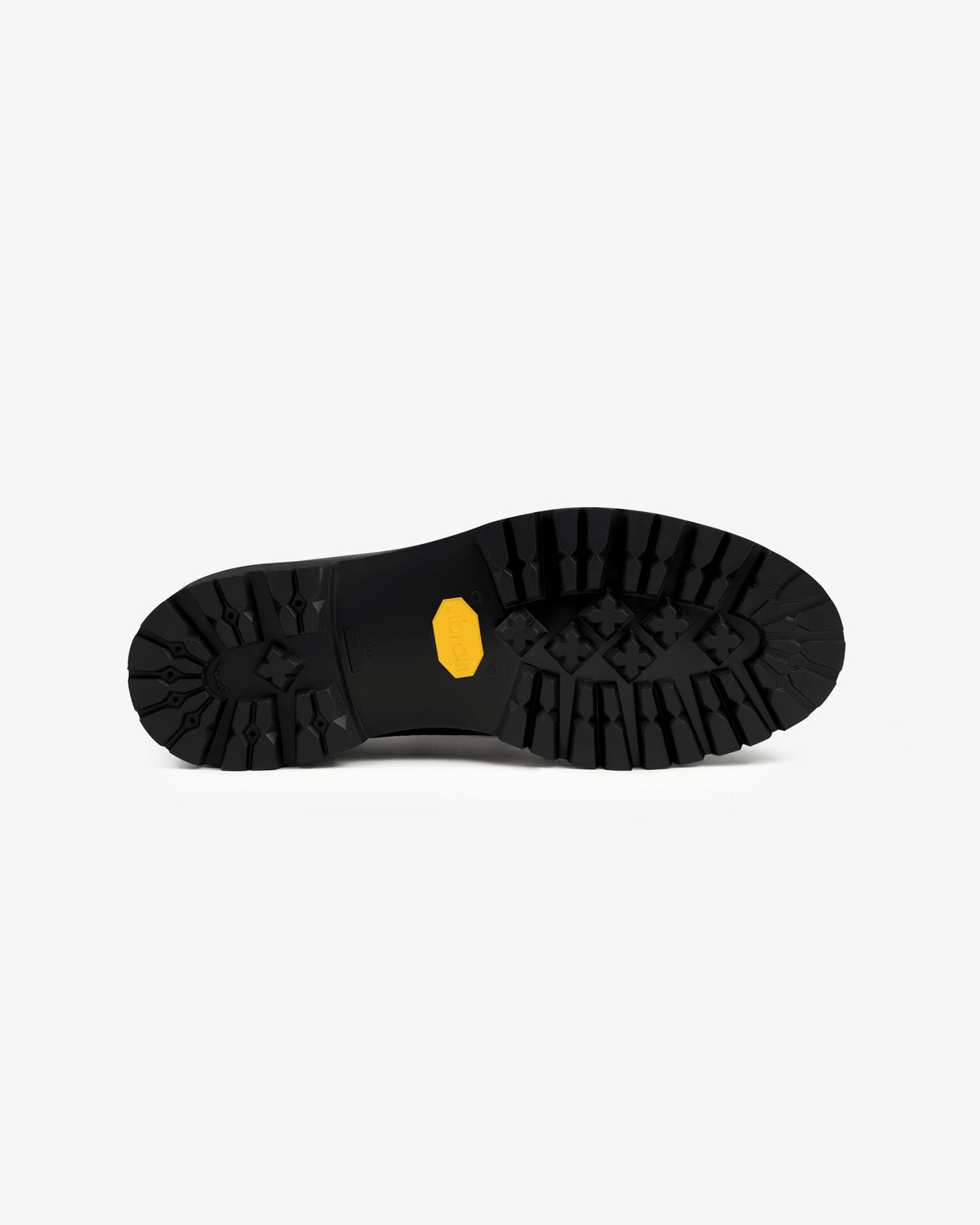 Black lugged rubber sole of a Field Boot with a yellow logo emblem in the center.