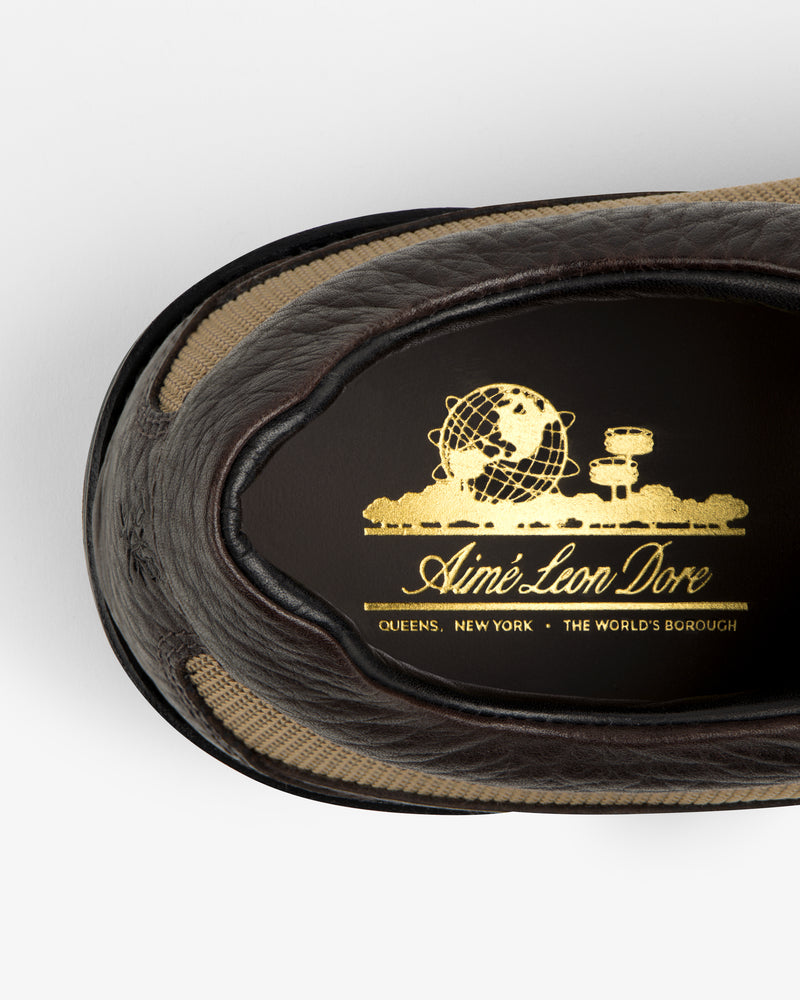 Interior view of a dark brown Field Boot featuring a gold globe emblem and the brand name Aimé Leon Dore.