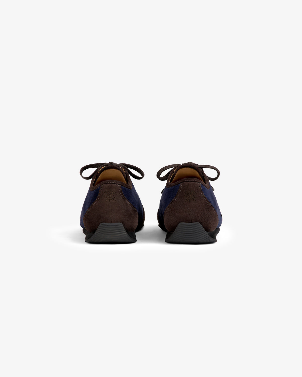 Back view of two Low Profile Suede Trainer navy and brown suede shoes with black soles.