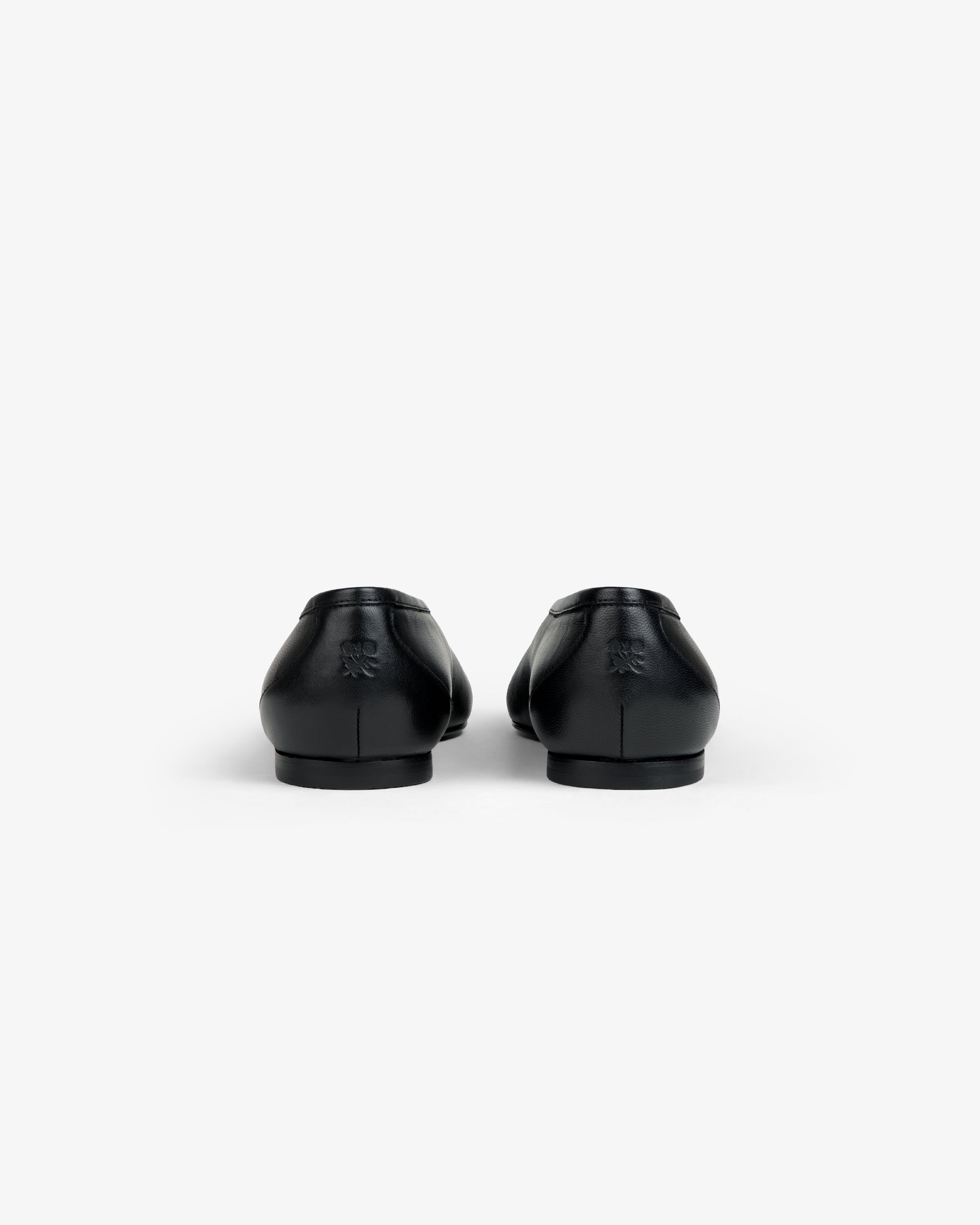 Back view of black Leather Ballet Flat shoes featuring a small embossed logo on the heels.