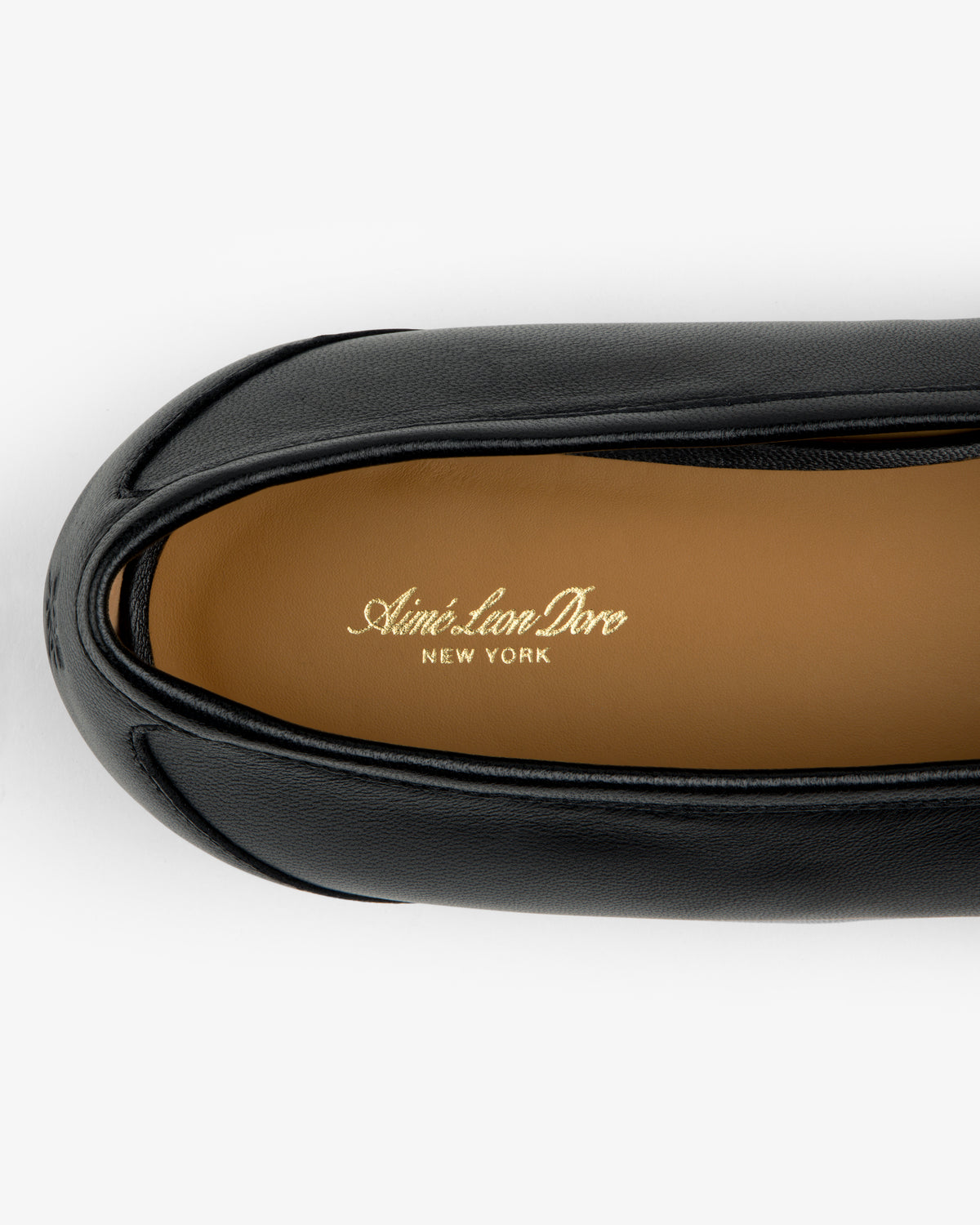 Top-down view of a black Leather Ballet Flat showing a tan insole stamped with gold text.