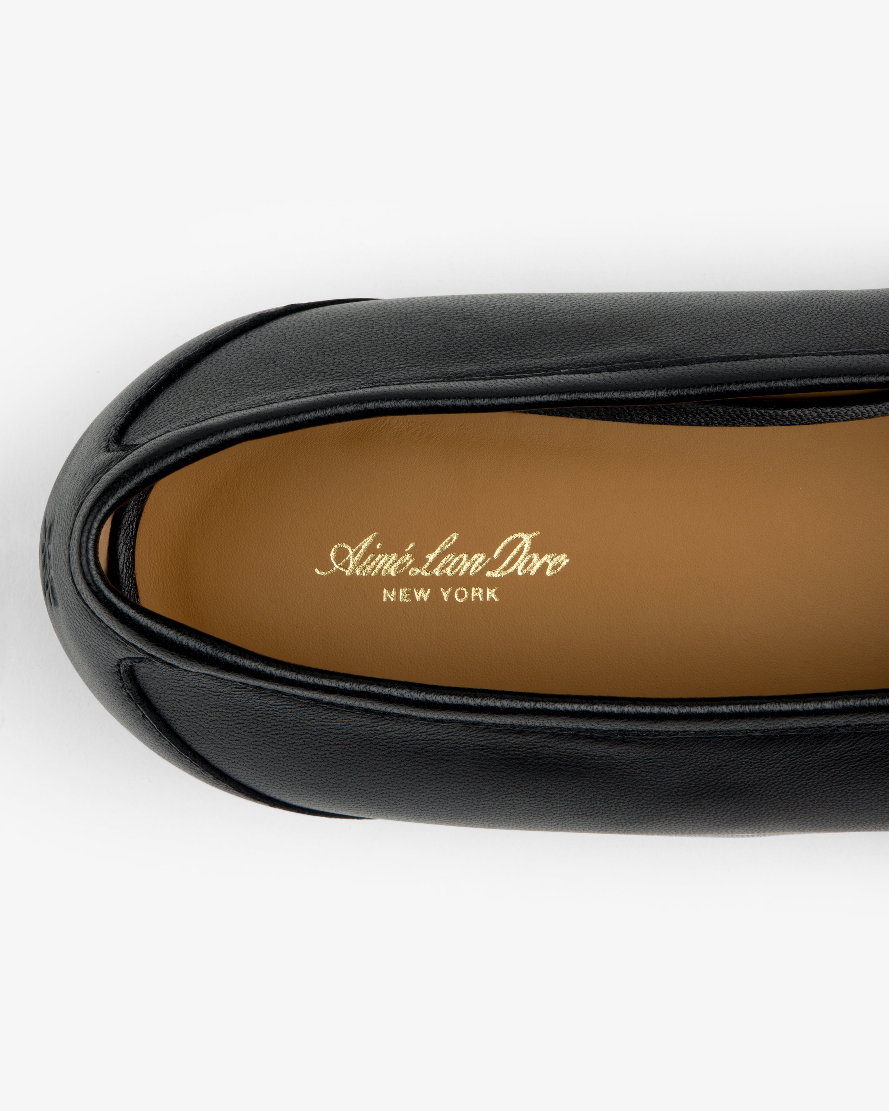 Top-down view of a black Leather Ballet Flat showing a tan insole stamped with gold text.