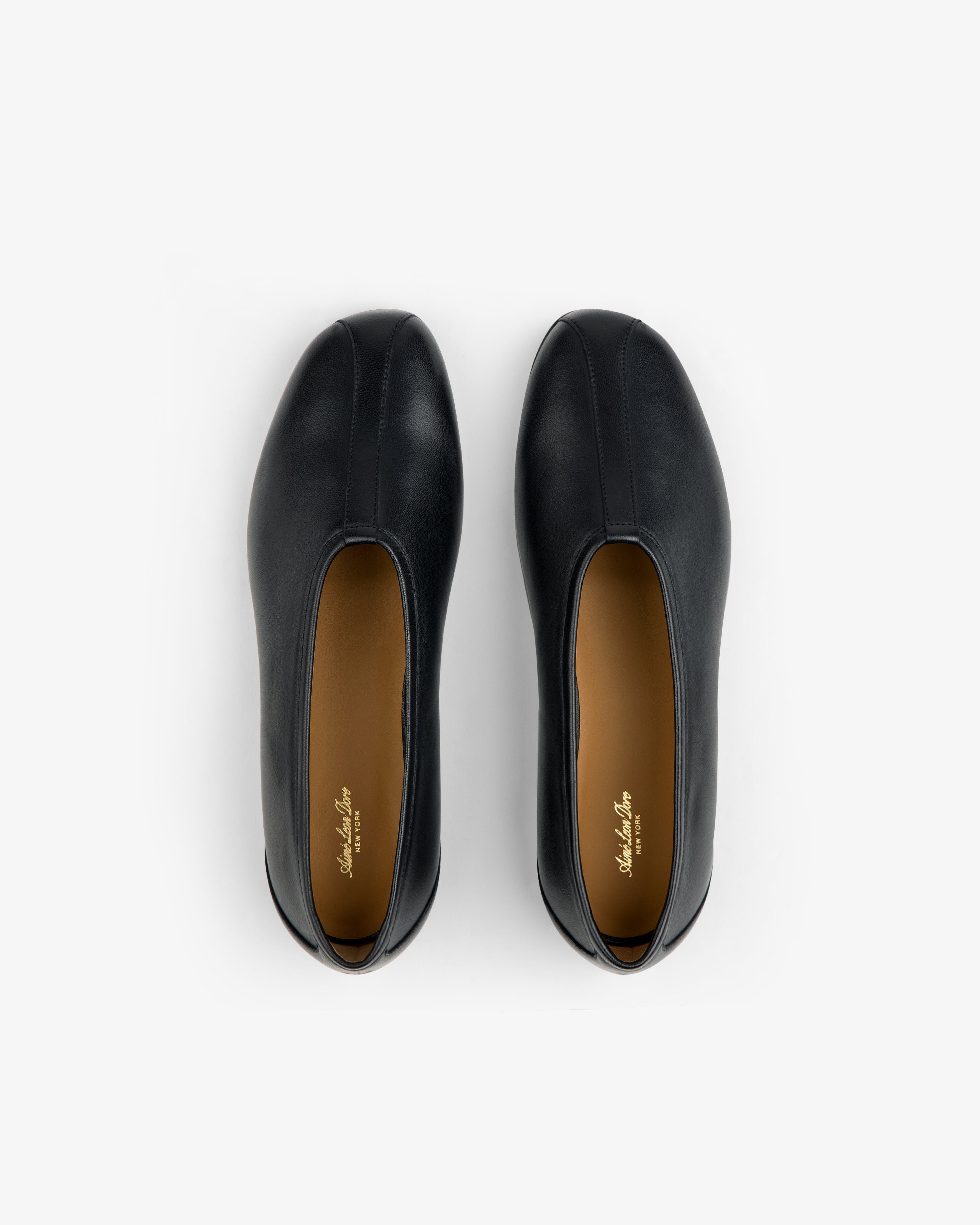 Top-down view of Leather Ballet Flat black shoes with tan insoles.