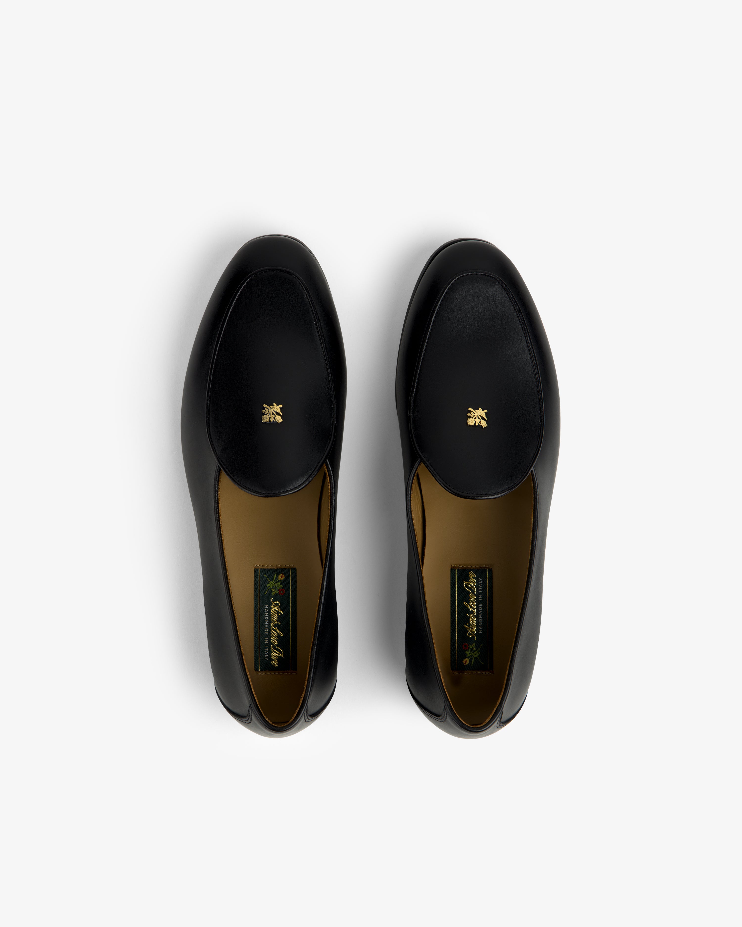 Crest Salóni Loafers—black leather, gold emblems on uppers, photographed from above on a white background.