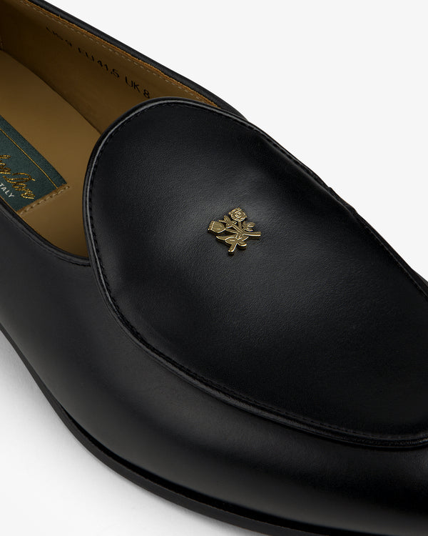 Crest Salóni Loafer: black leather with a gold floral emblem on the upper front.