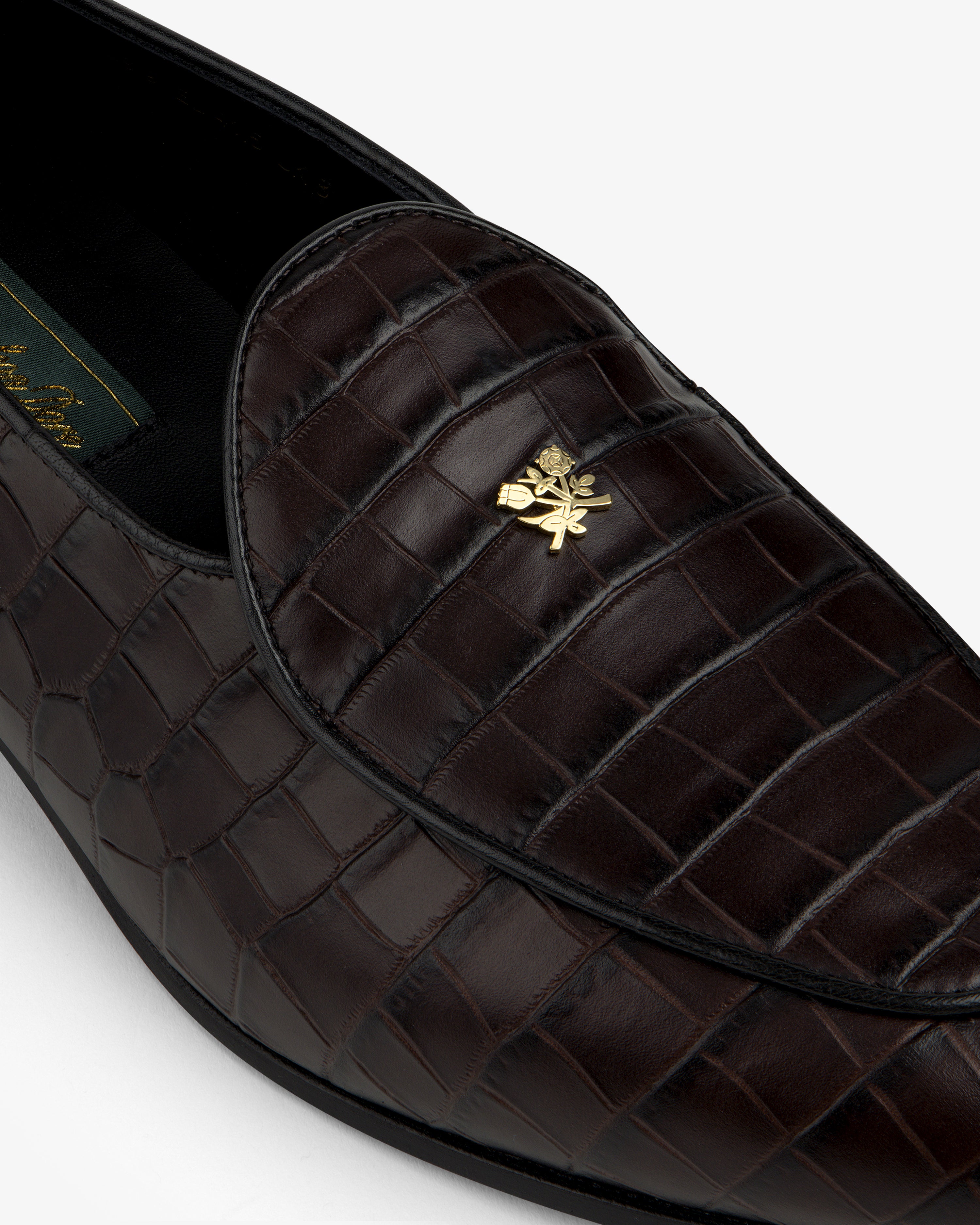 Close-up of the Croc-Embossed Crest Salóni Loafer featuring dark brown crocodile pattern and gold emblem.