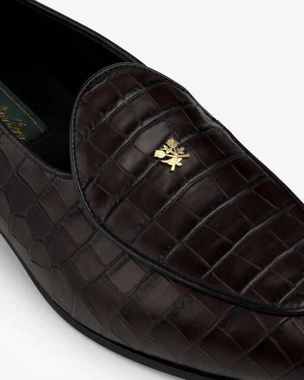 Close-up of the Croc-Embossed Crest Salóni Loafer featuring dark brown crocodile pattern and gold emblem.