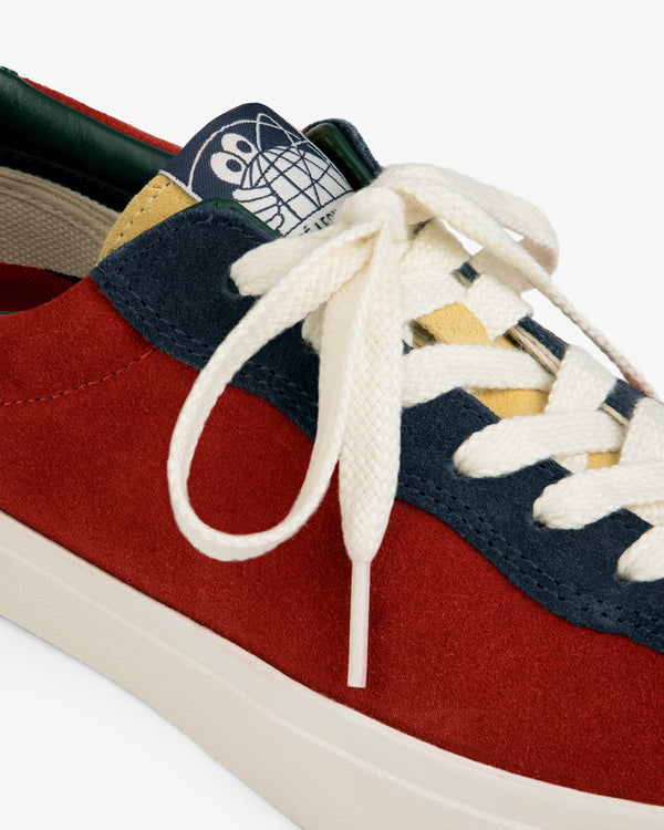 ALD / Last Resort AB VM001-LO Suede: red, navy & cream sneaker with white laces, cartoon face on tongue. Close-up view.