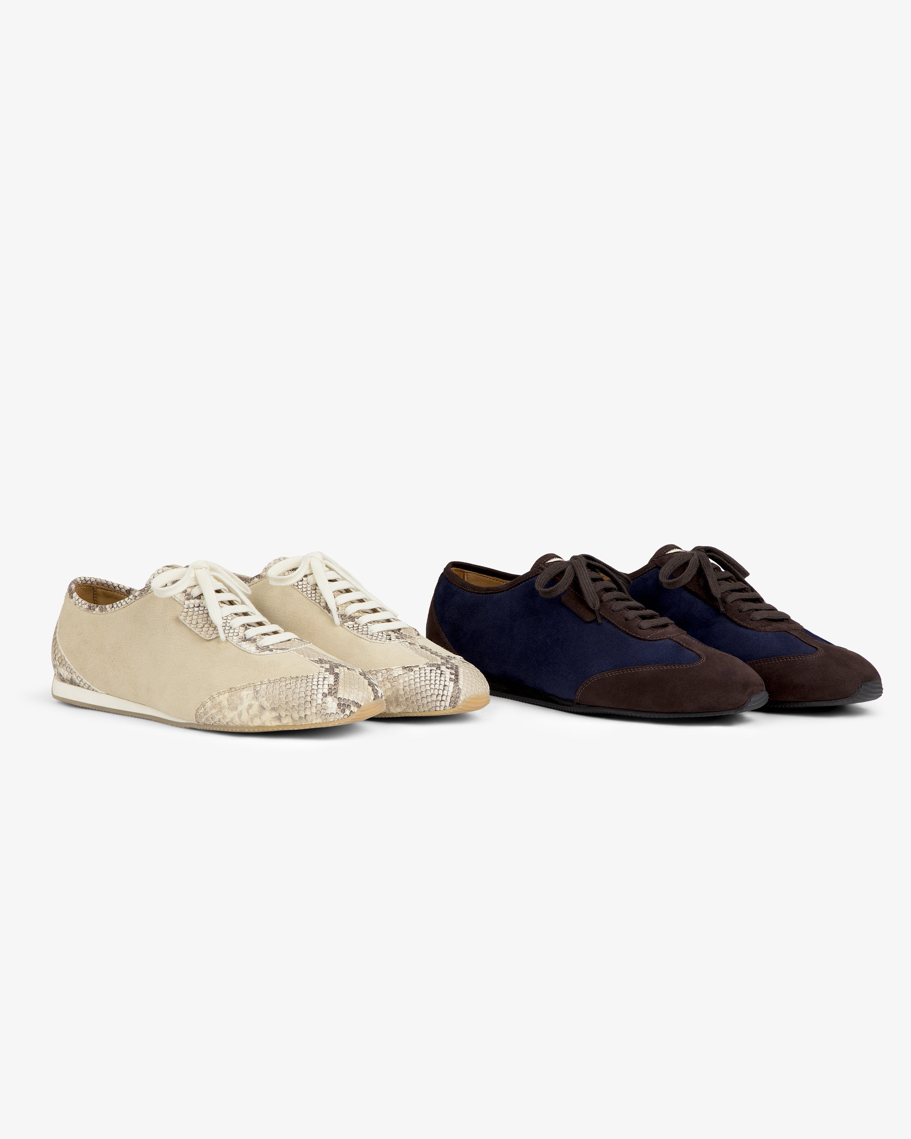 Two pairs of Low Profile Suede Trainer: one in beige snakeskin texture, and one in navy and dark brown.