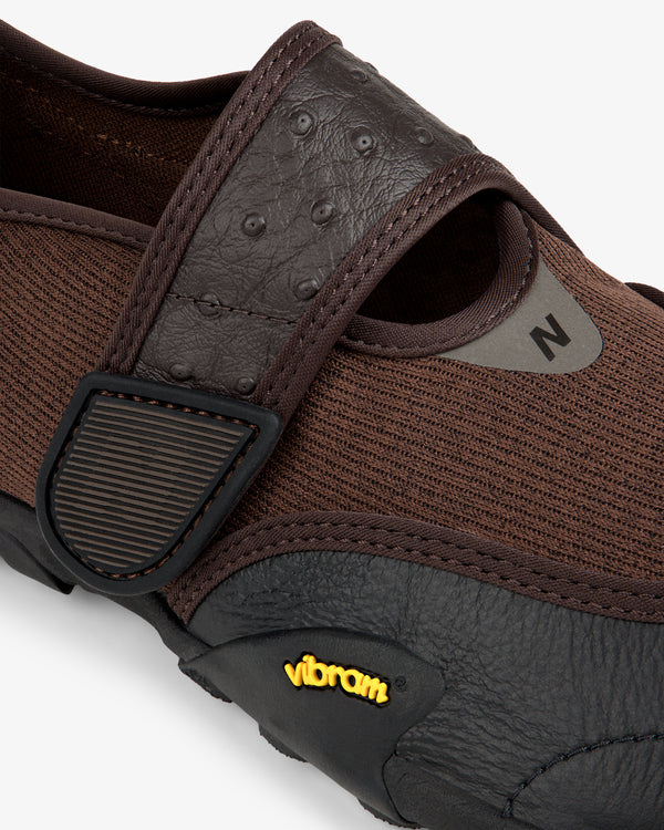 ALD / New Balance MT2 dark brown mesh slip-on shoe with an adjustable strap, textured leather accents, and Vibram sole.