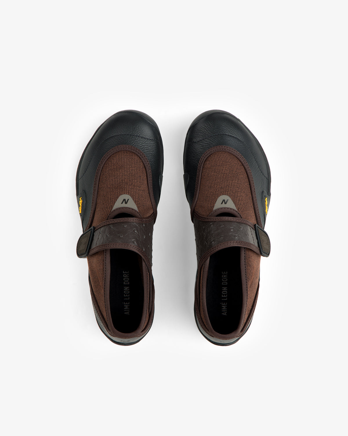 Top-down view of brown and black ALD / New Balance MT2 slip-on shoes with hook-and-loop closures and yellow Vibram tags.